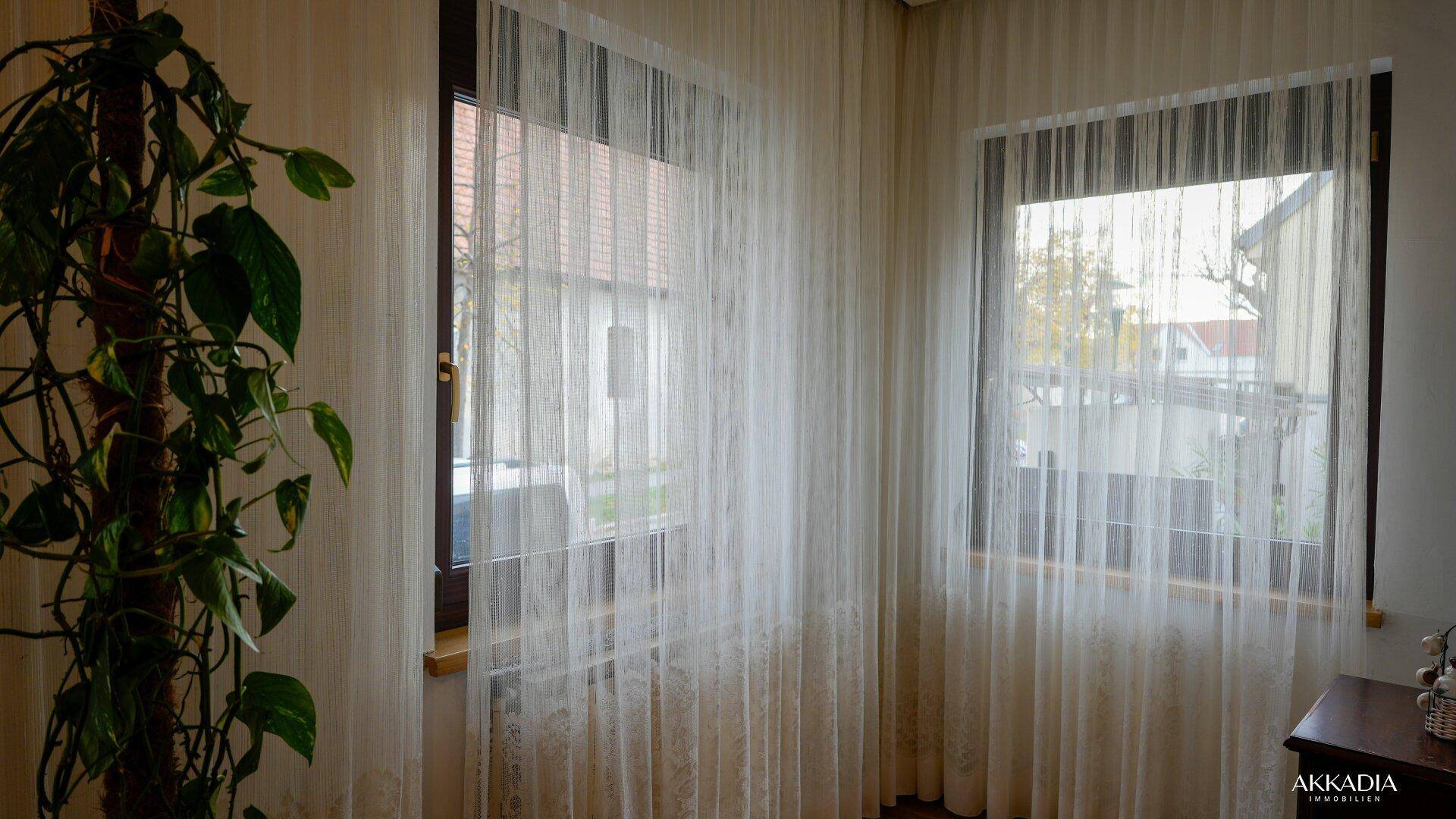 Große Fenster mit hellen Vorhängen, die viel Tageslicht hereinlassen.