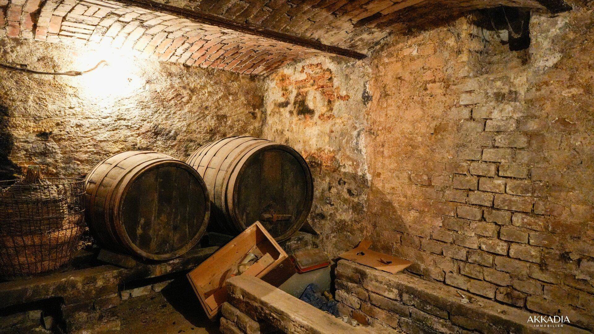 Historischer Weinkeller mit Ziegelgewölbe und Holzfässern, ideal zur Weinlagerung.