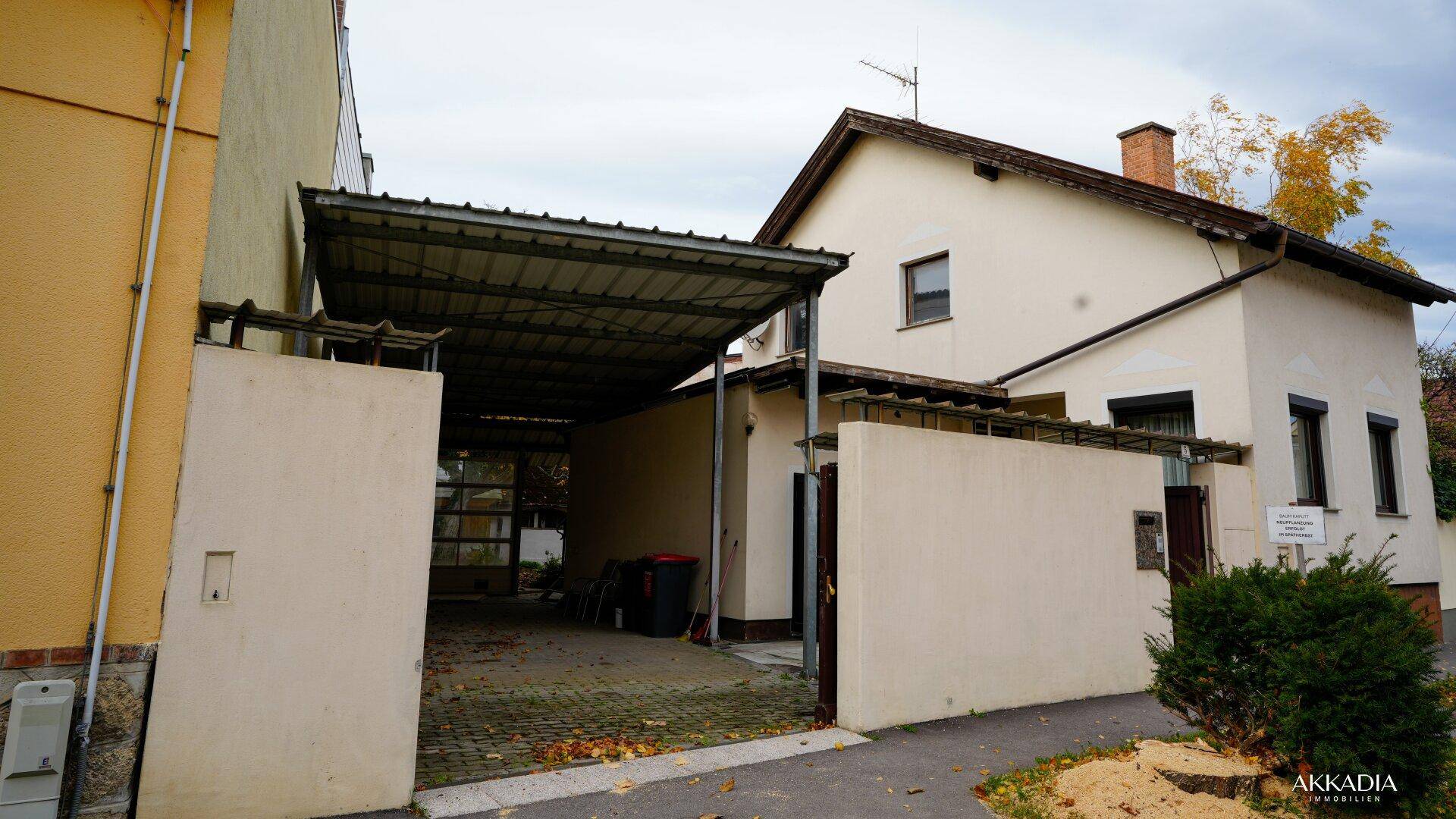 Seitenansicht des Hauses mit überdachtem Carport und Zugang zum Innenhof.