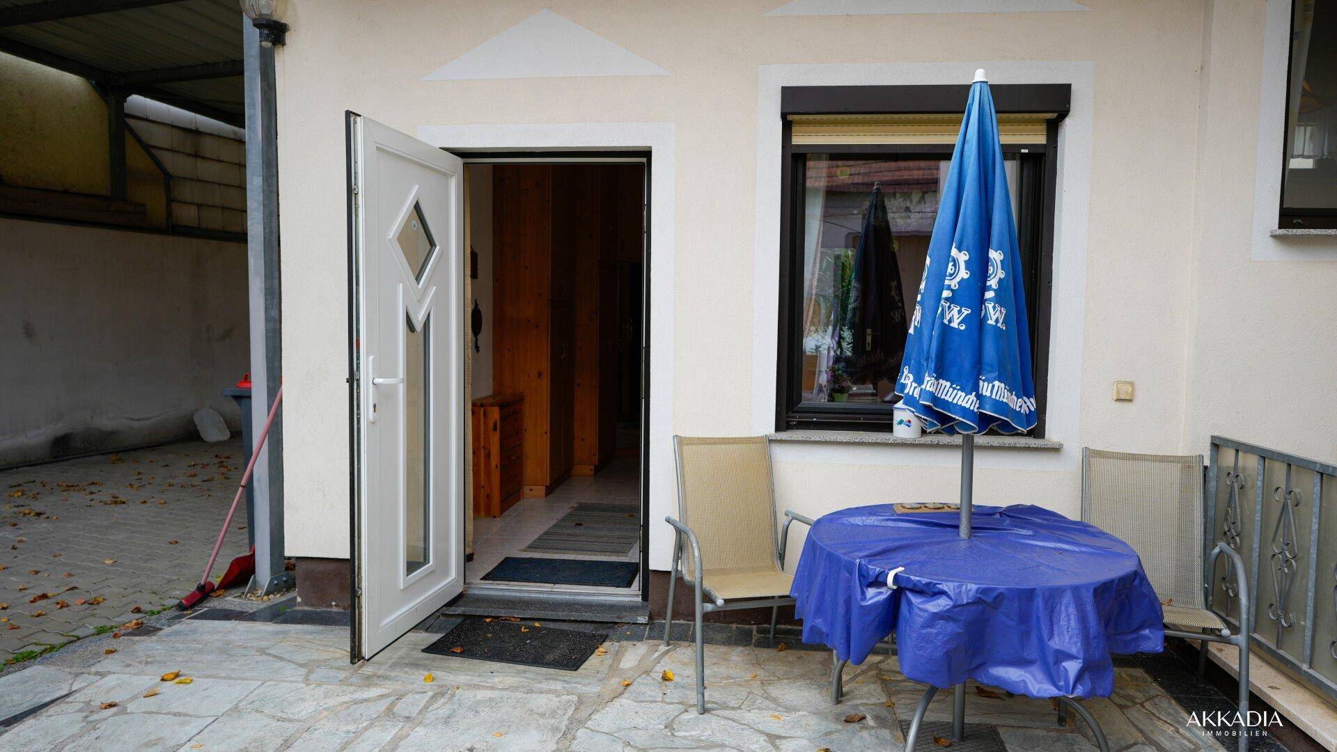 Eingangsbereich zum Haus vom Innenhof aus mit Sitzgelegenheiten und Sonnenschirm.