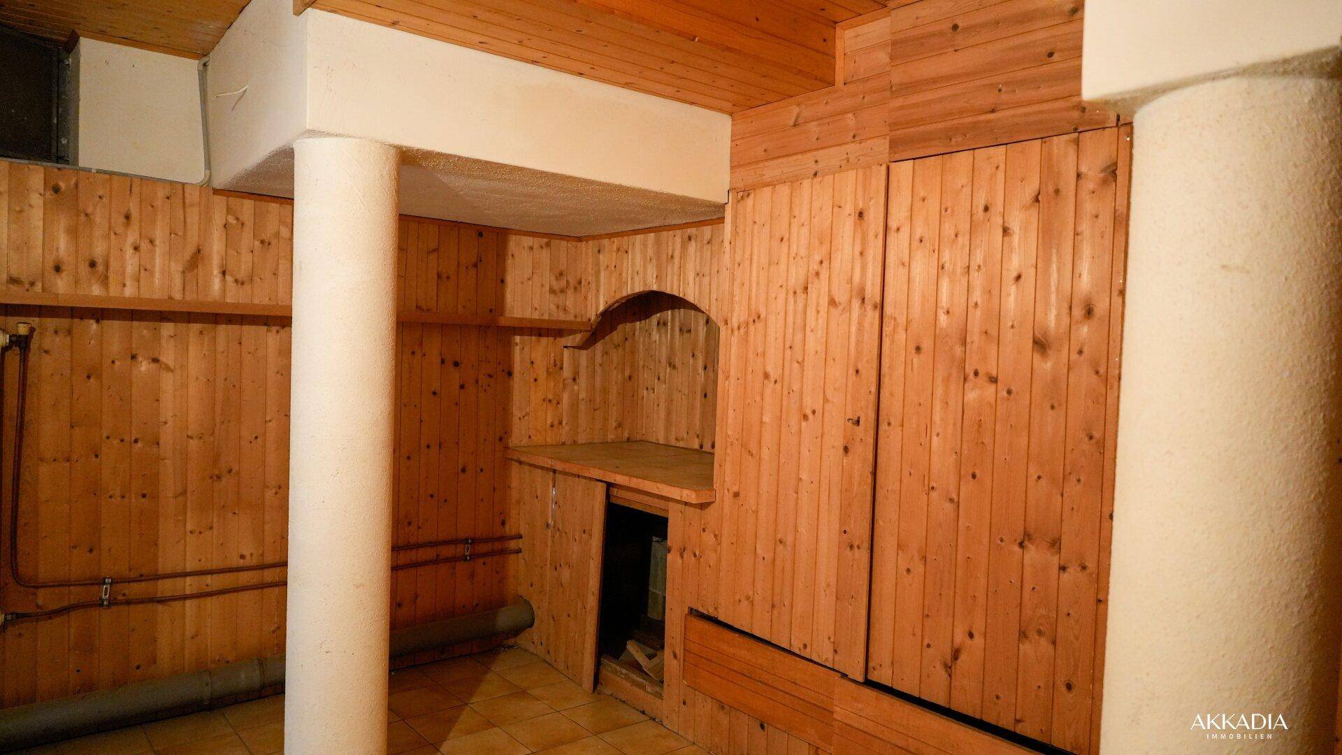 Kellerraum mit Holzvertäfelung und Nischen, geeignet für Lagerung oder Werkstatt.