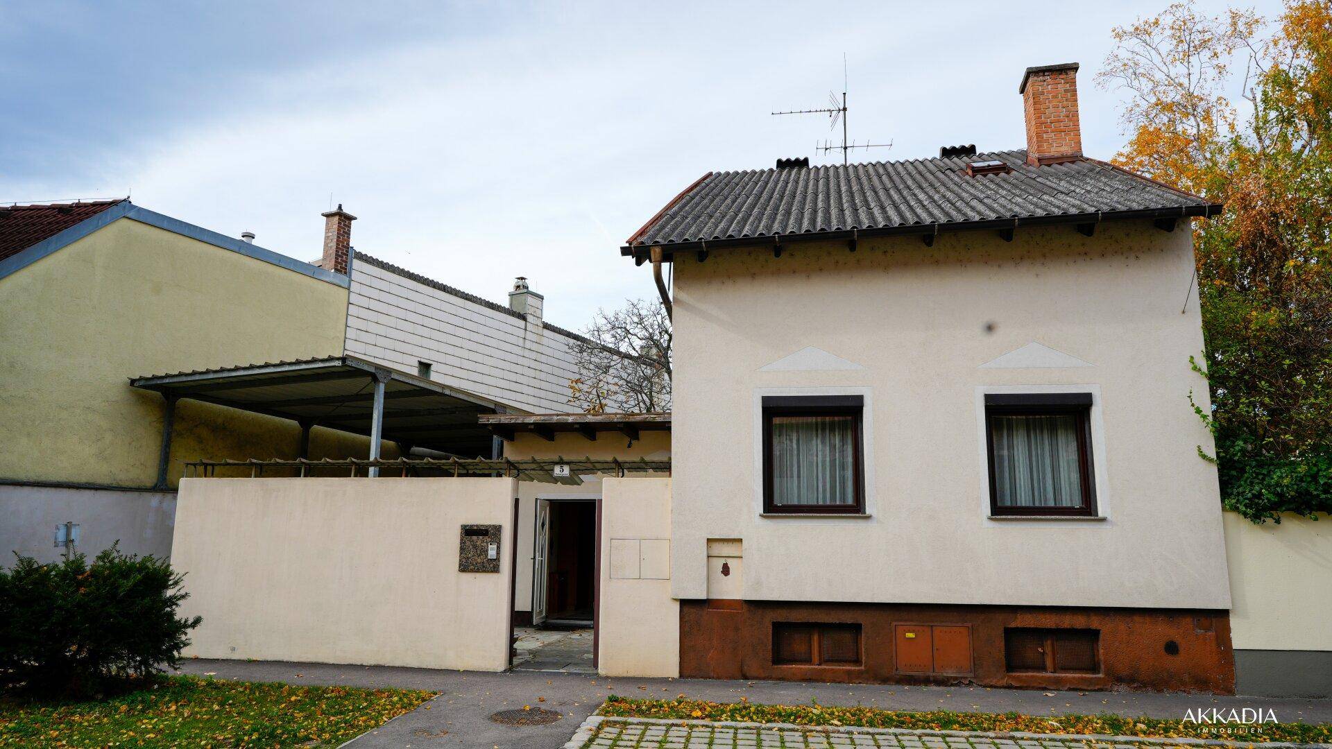Vorderansicht des Hauses mit gepflegtem Vorgarten und Carport-Einfahrt.