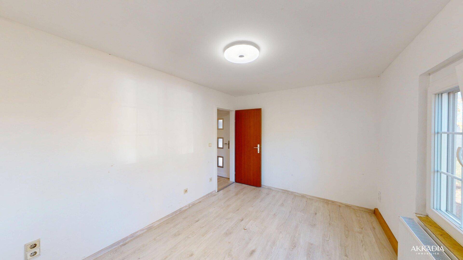 Geräumiges Schlafzimmer mit hellem Laminatboden und Zugang zum Flur.