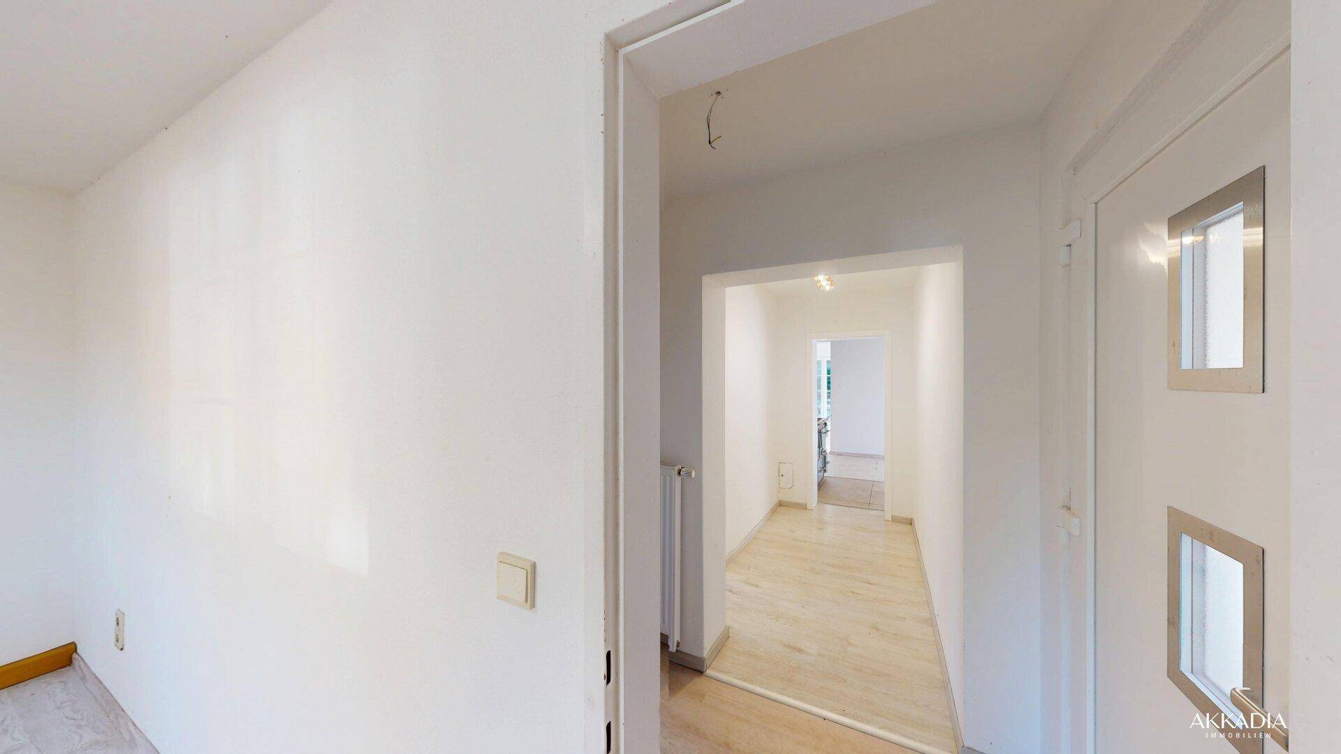 Heller Eingangsbereich mit Laminatboden und Türen zu angrenzenden Zimmern.