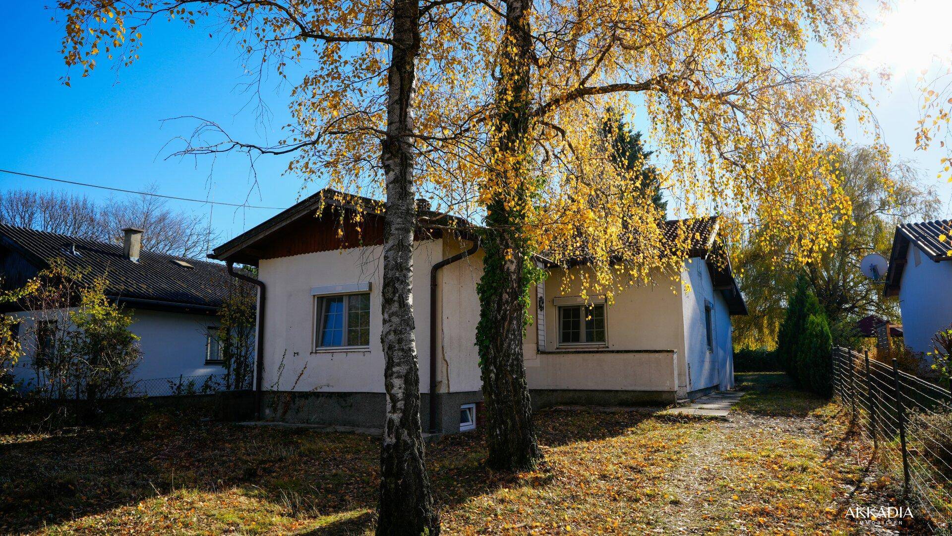 Einfamilienhaus mit traditionellem Satteldach und herbstlicher Umgebung.