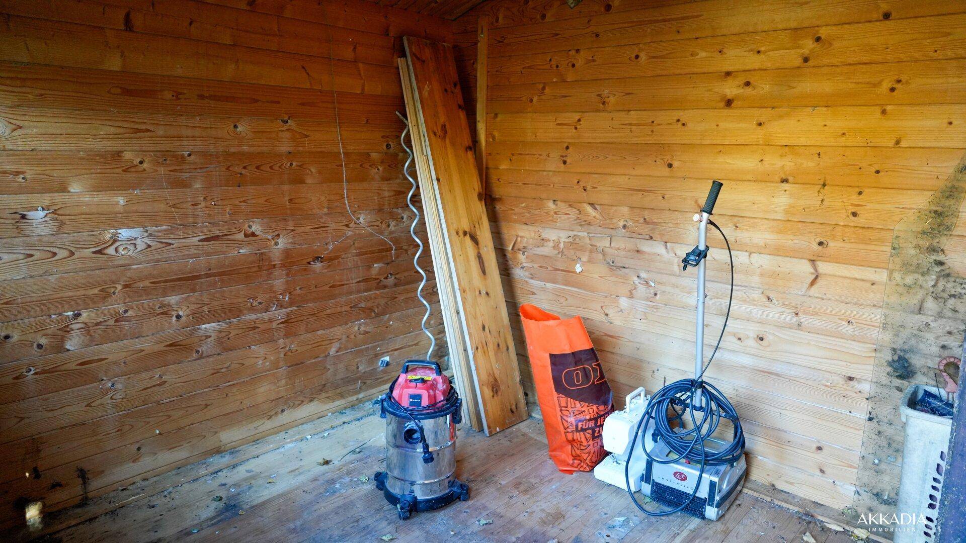 Innenansicht des Holzschuppens mit Holzverkleidung und Werkzeugen.