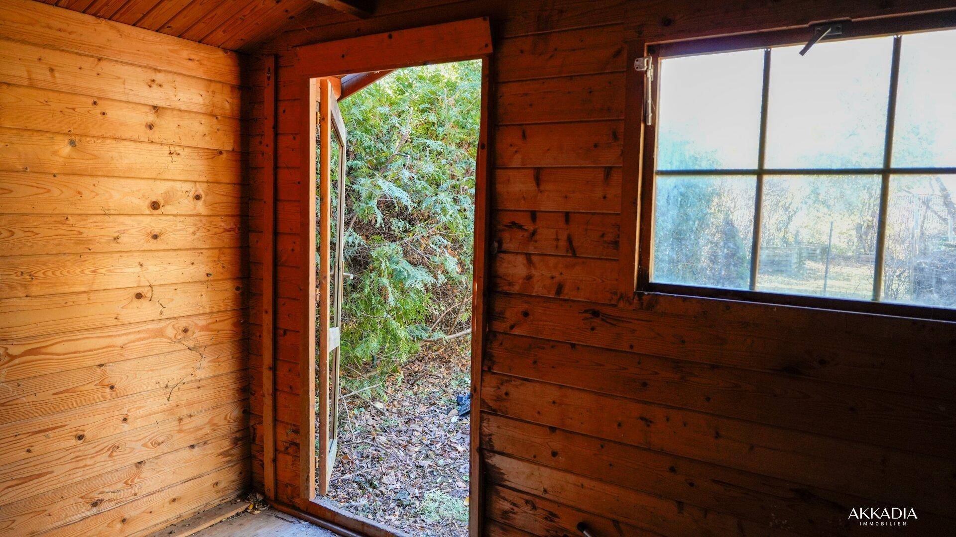 Innenansicht des Holzschuppens mit Blick nach draußen und Holzverkleidung.