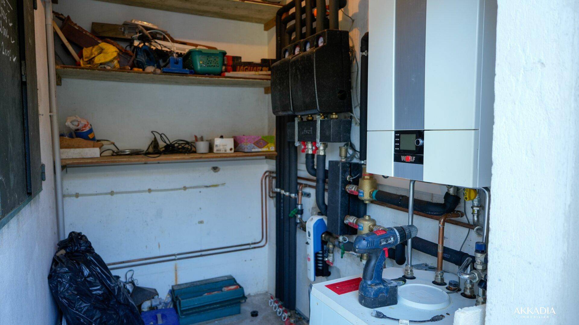 Technikraum mit Heizungsanlage, Rohren und Regalen für Lagerung.