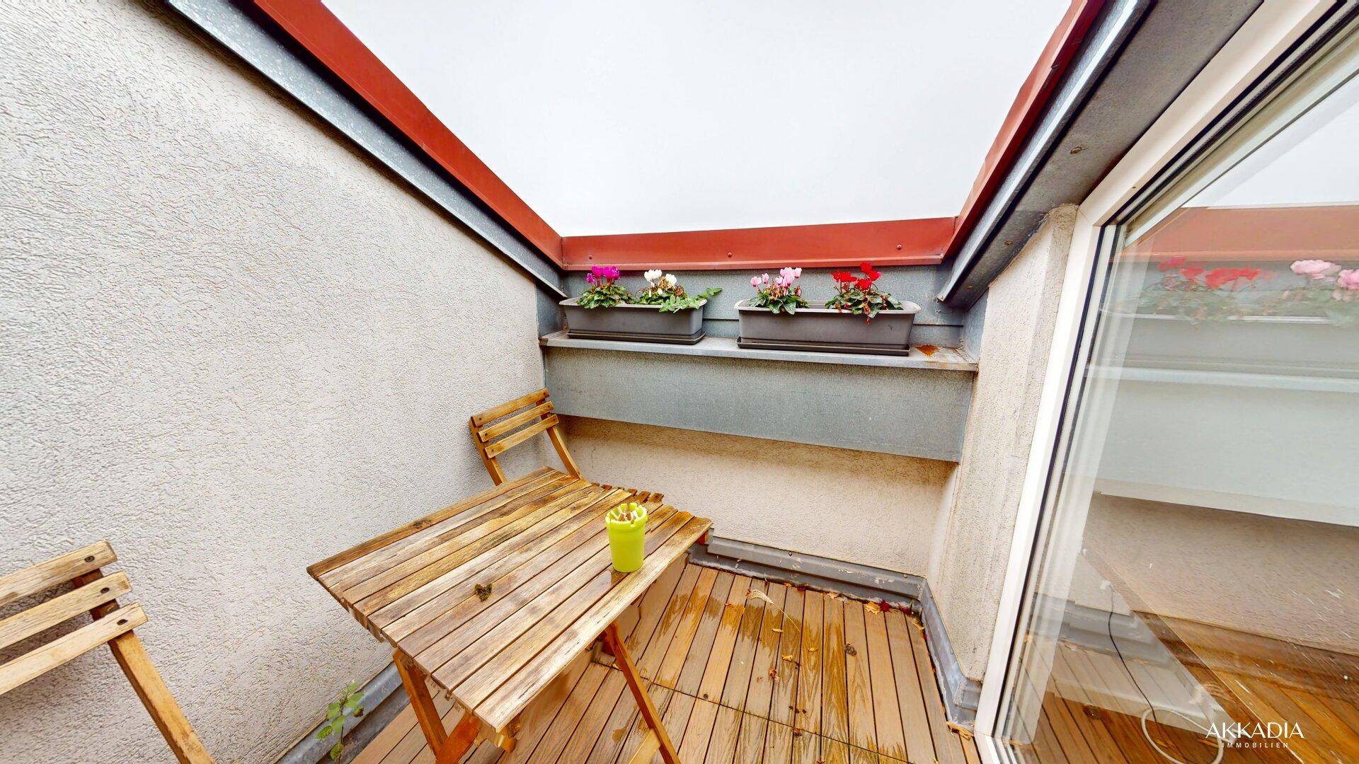 Kleiner, gemütlicher Balkon mit Holzboden und Blumenkästen, ideal für entspannte Momente.