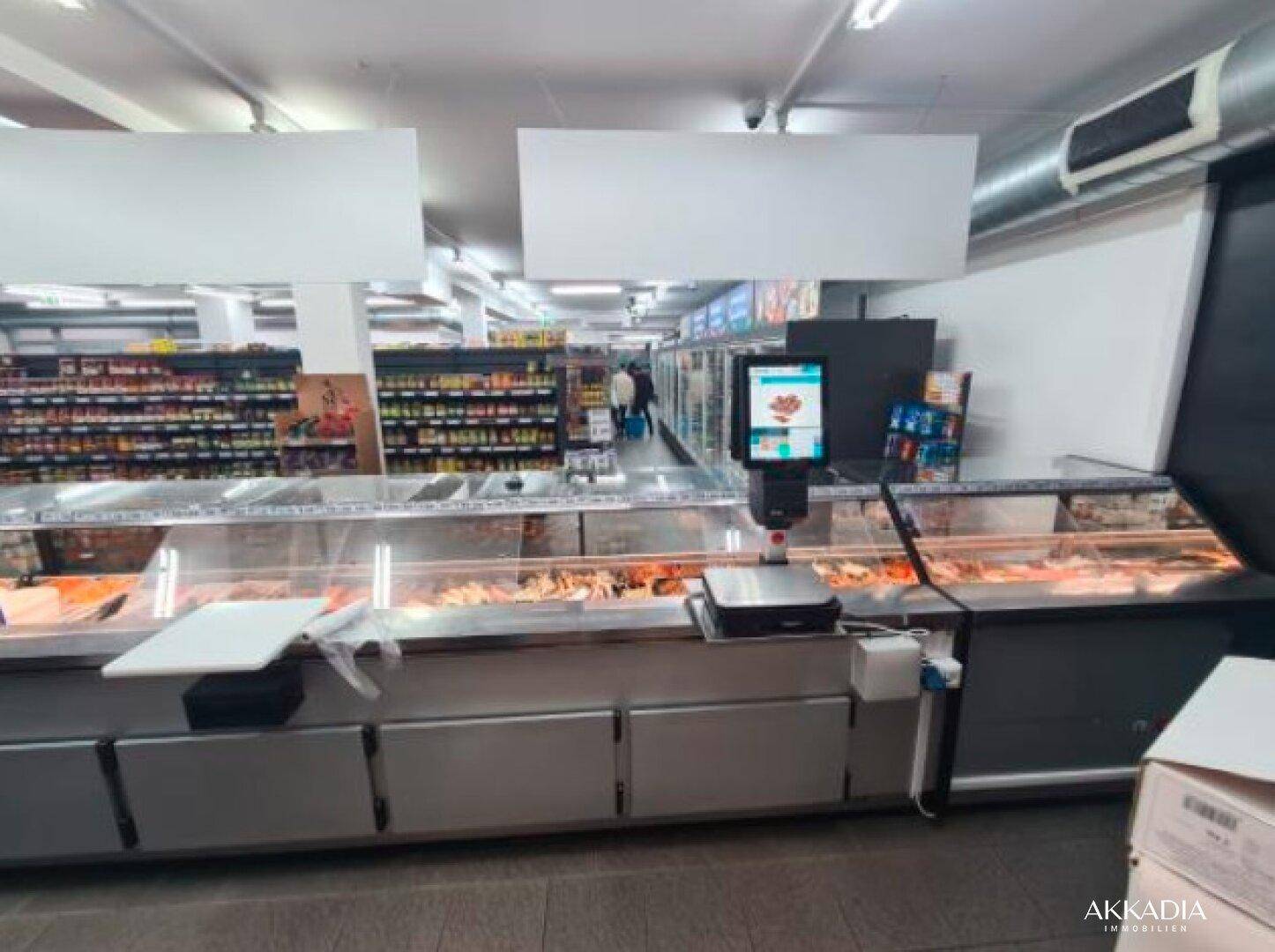 Der Hauptverkaufsraum eines Supermarktes mit langen Kühltheken und Regalen voller Produkte, gut beleuchtet.