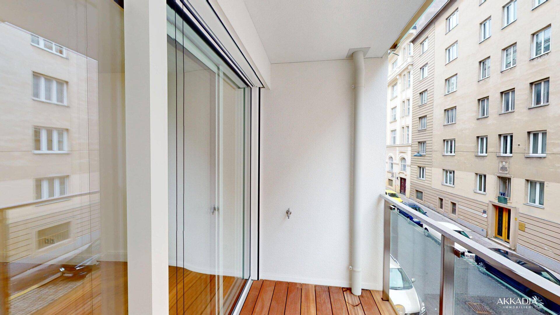 Moderner Balkon mit Holzfußboden, Glasgeländer und Außenjalousie, mit Blick auf die Stadt.