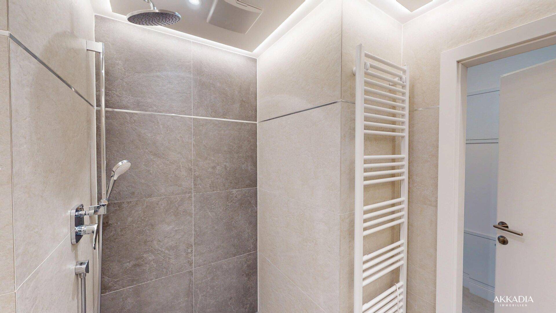 Moderne Dusche mit Regenduschkopf und beheiztem Handtuchhalter in einem hellen Badezimmer.