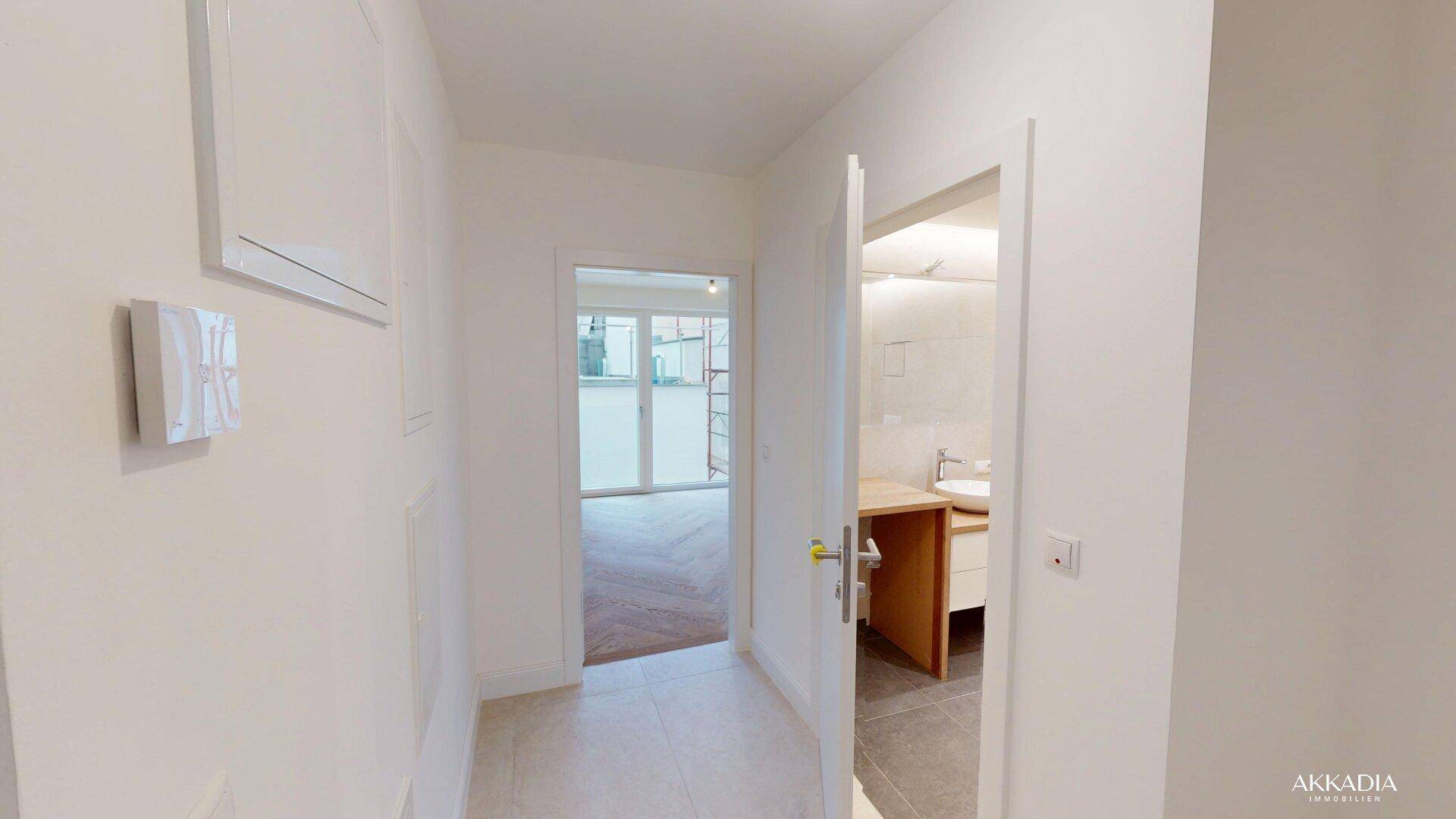 Heller Flur mit Fliesenboden, der einen Blick ins Badezimmer und den Wohnbereich bietet.