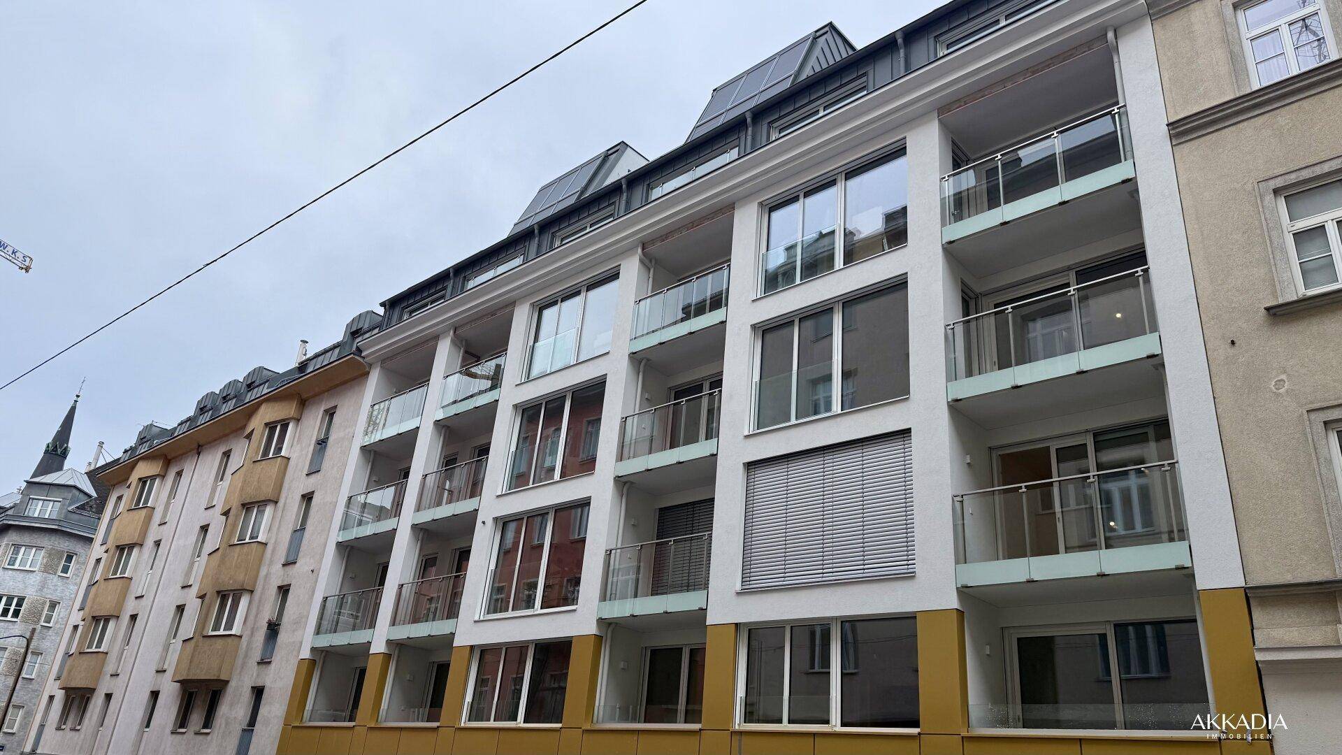 Ansicht der modernen Wohngebäude mit Balkonen und umliegender Stadtarchitektur unter bewölktem Himmel.
