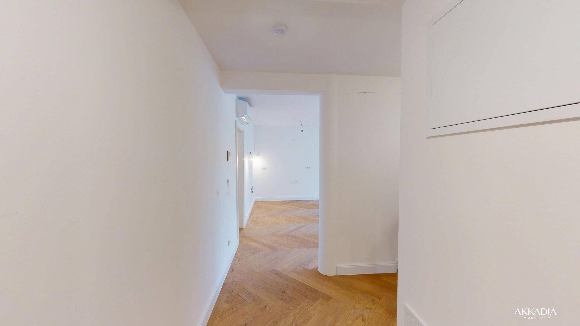 Heller Flur mit Fischgrätparkettboden, der zu weiteren Zimmern der Wohnung führt.