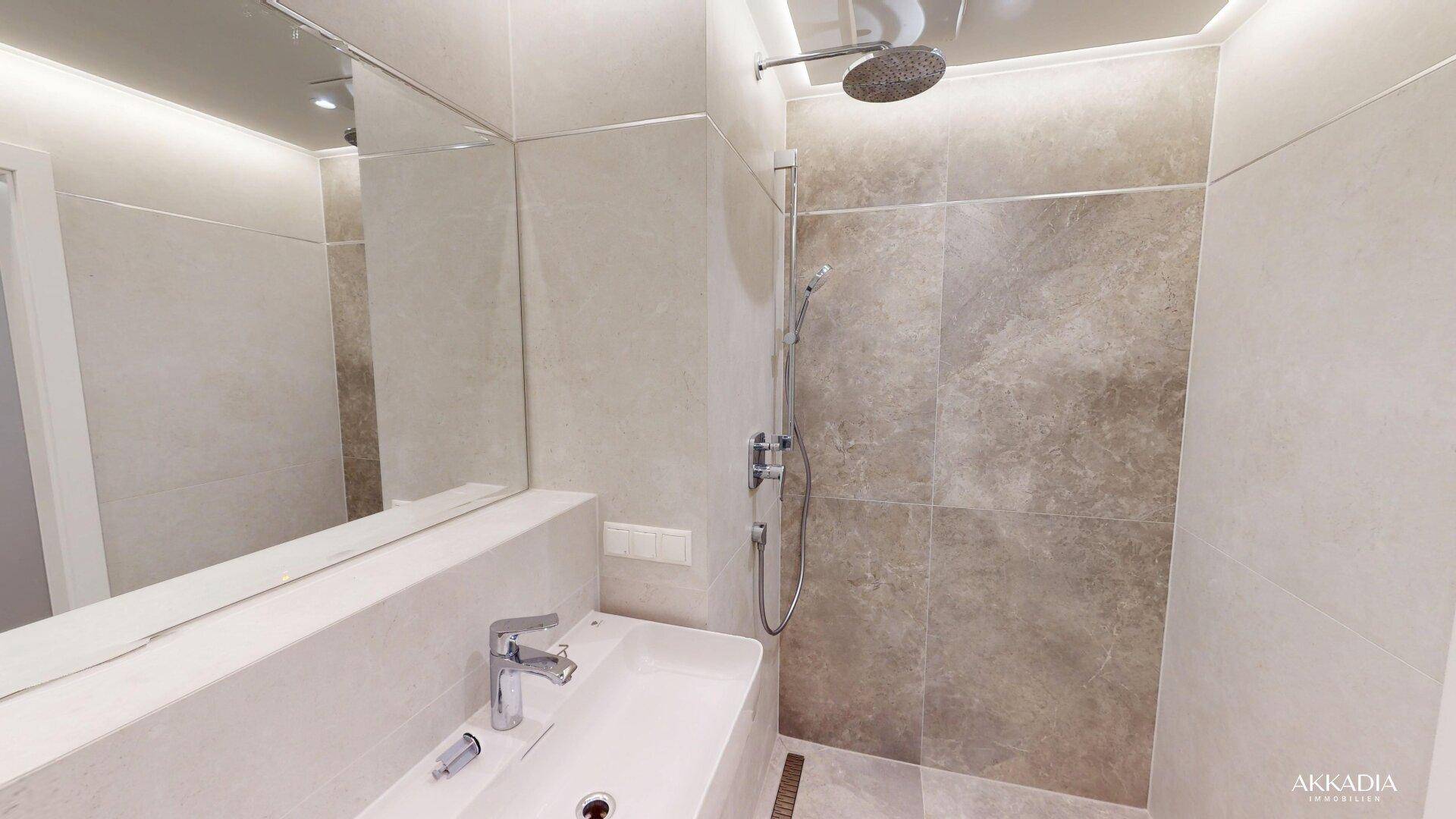 Detailansicht des modernen Badezimmers mit Regendusche, Waschtisch und großem Spiegel.