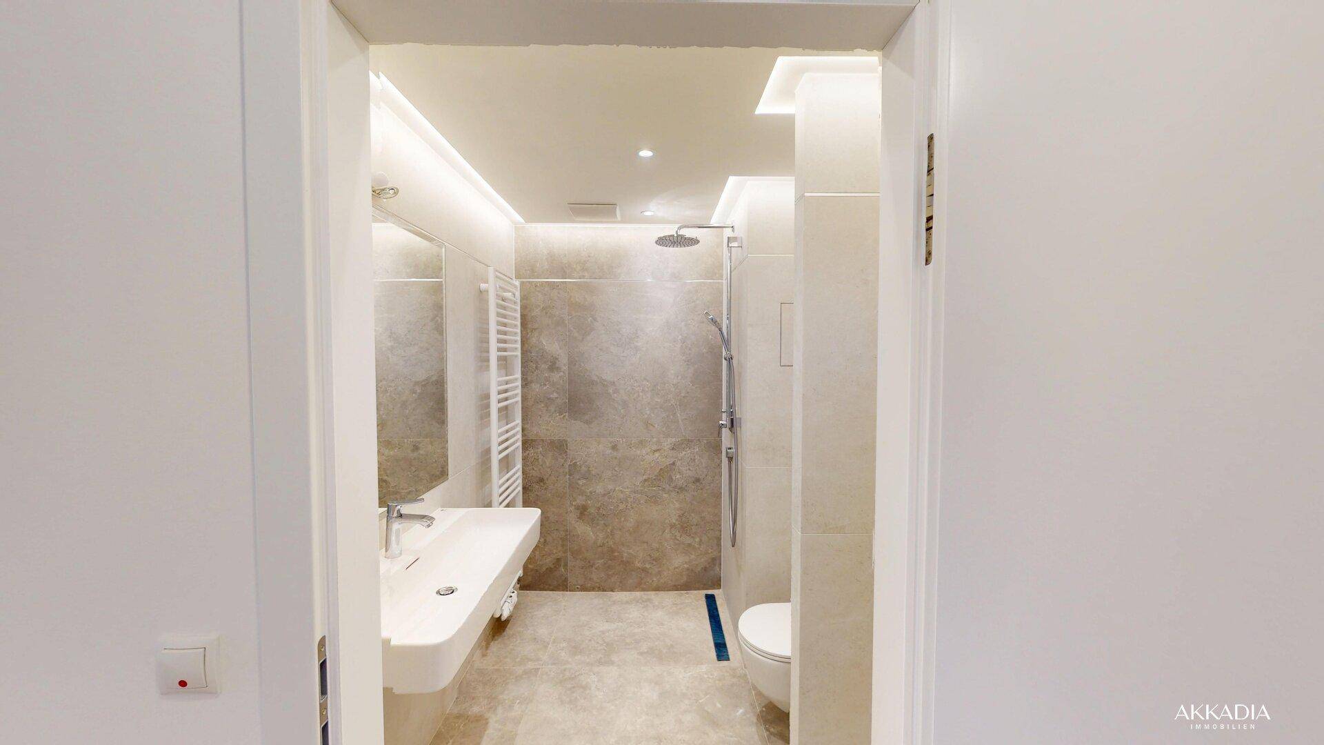 Modernes Badezimmer mit begehbarer Dusche, Wand-WC und eleganten großformatigen Fliesen.