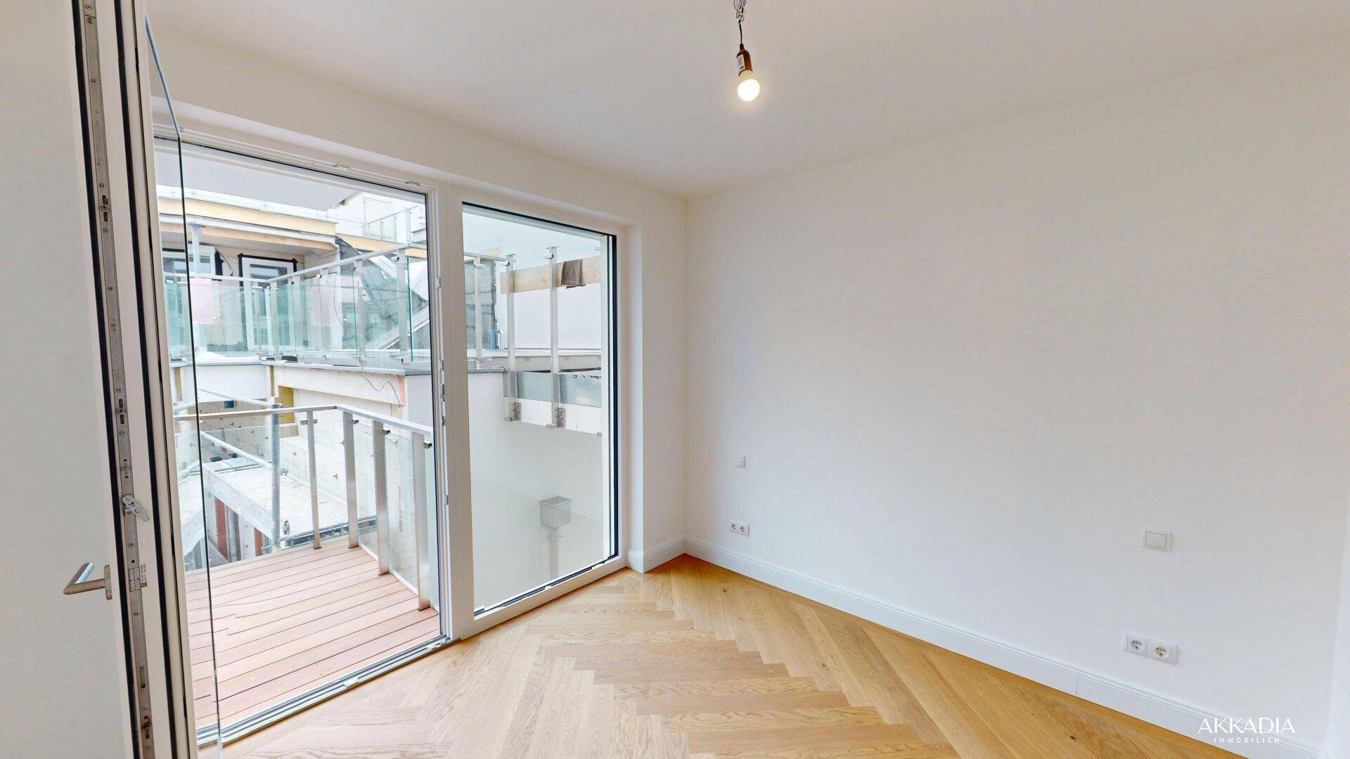 Ruhiger Raum mit Fischgrätparkett und direktem Zugang zu einem sonnigen Balkon.