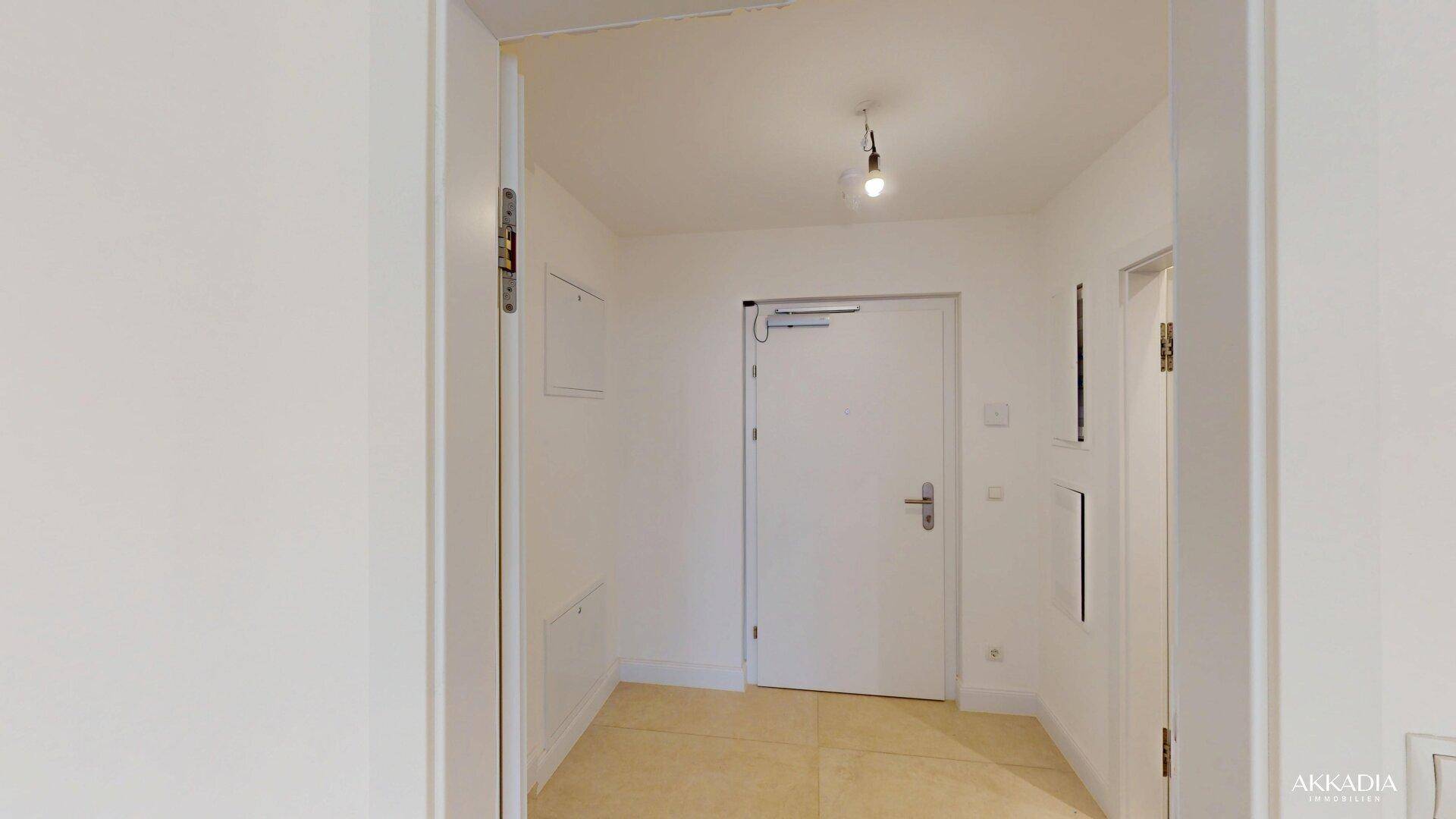 Eingangsbereich mit heller Fliesenboden und stabiler Eingangstür in einem Neubau.