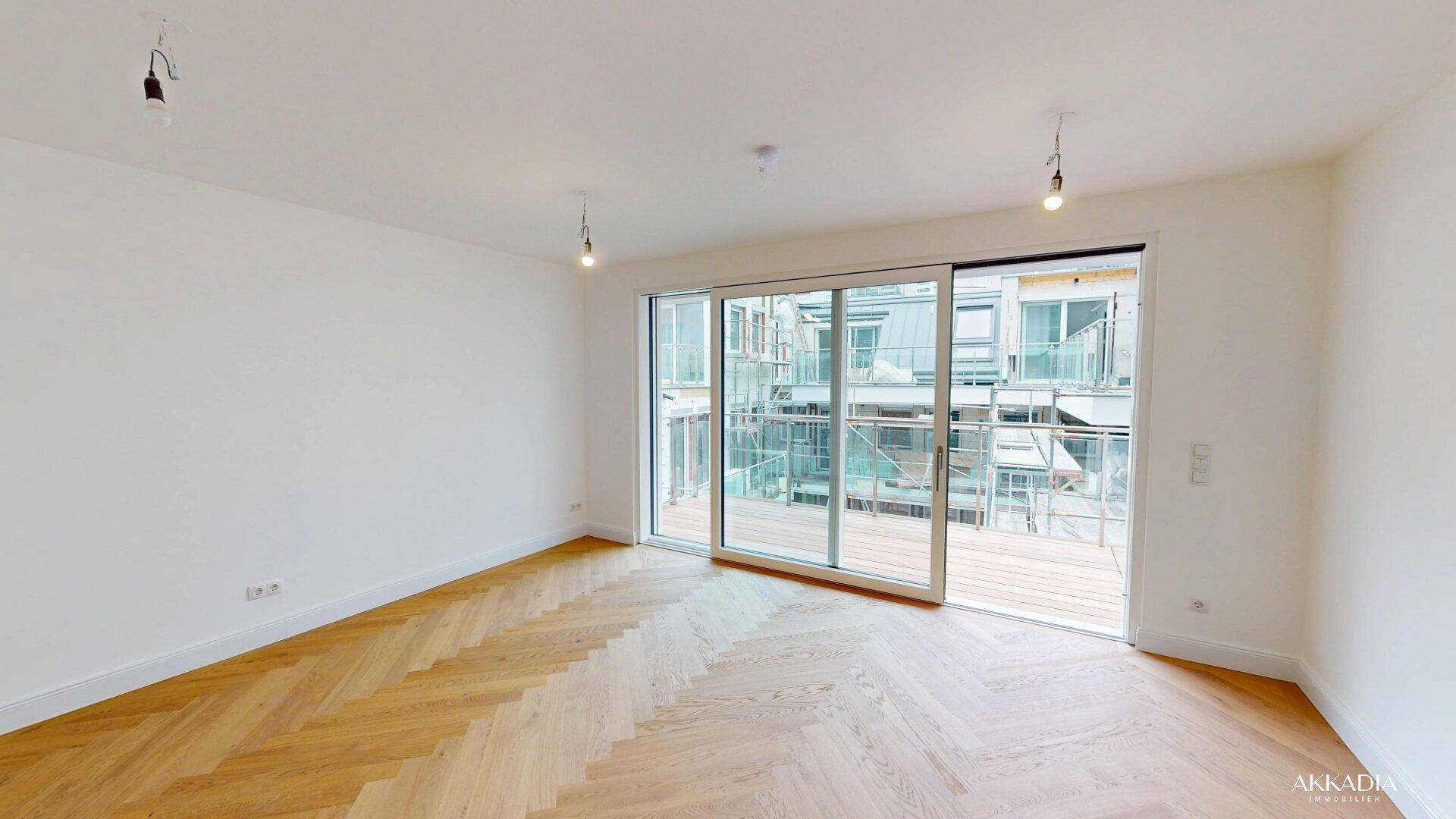 Lichtdurchfluteter Raum mit elegantem Fischgrätparkett und breiter Glasfront zum Außenbereich.