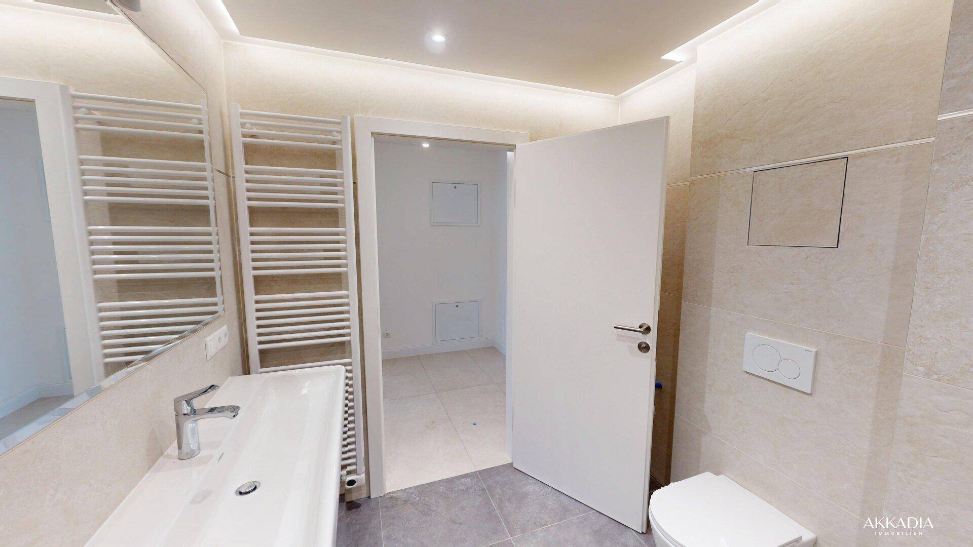 Modernes Badezimmer mit eleganten Fliesen, wandhängendem WC und beheiztem Handtuchhalter.