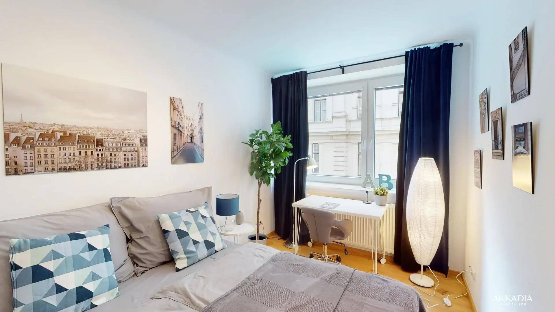 Gemütliches Schlafzimmer mit Bett, Schreibtisch und Blick auf die Stadt.