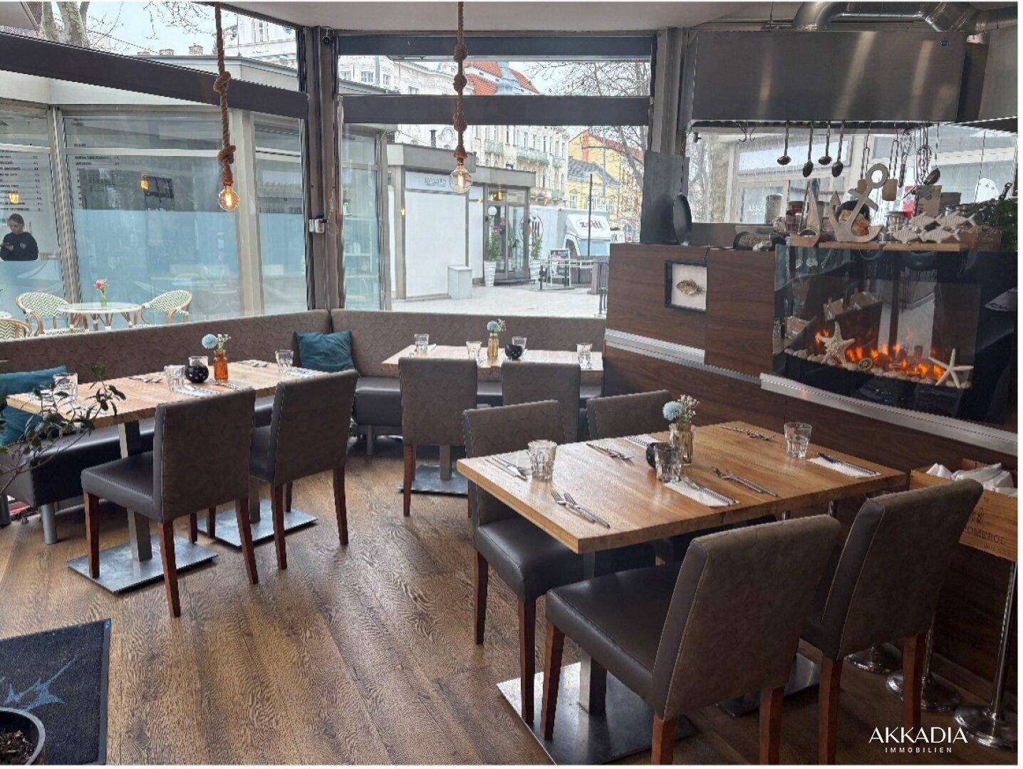 Gemütlicher Restaurantbereich mit Holztischen, bequemen Sitzbänken und dekorativem Kamin.