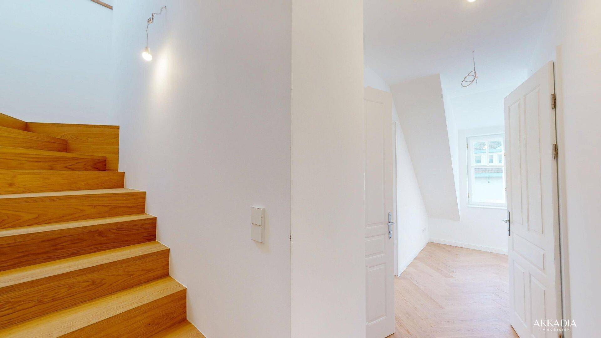 Moderne Holztreppe führt in den oberen Bereich, angrenzend an einen hellen Raum.