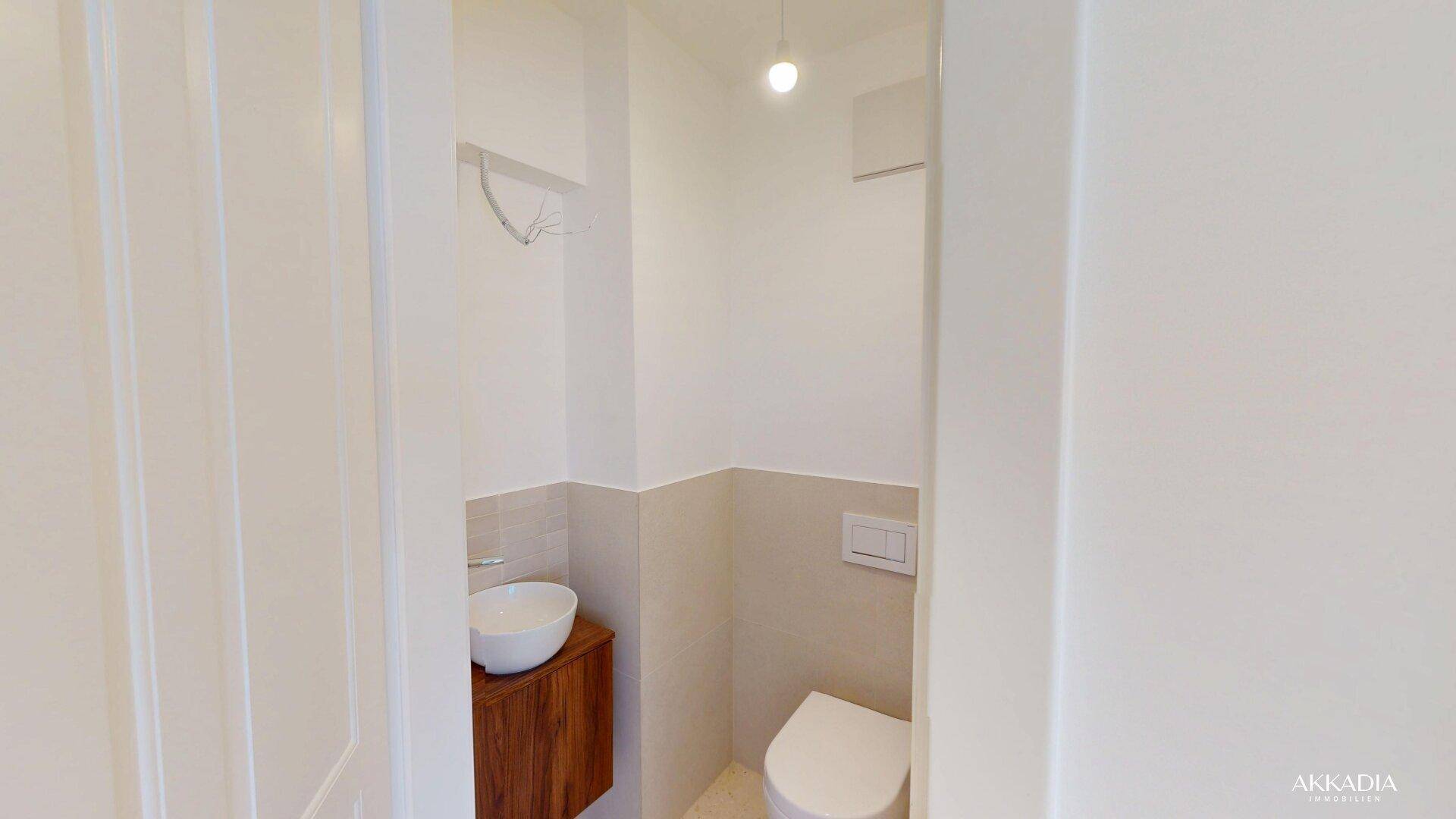 Modernes Gäste-WC mit wandhängendem WC, Aufsatzwaschbecken und Holzunterschrank.