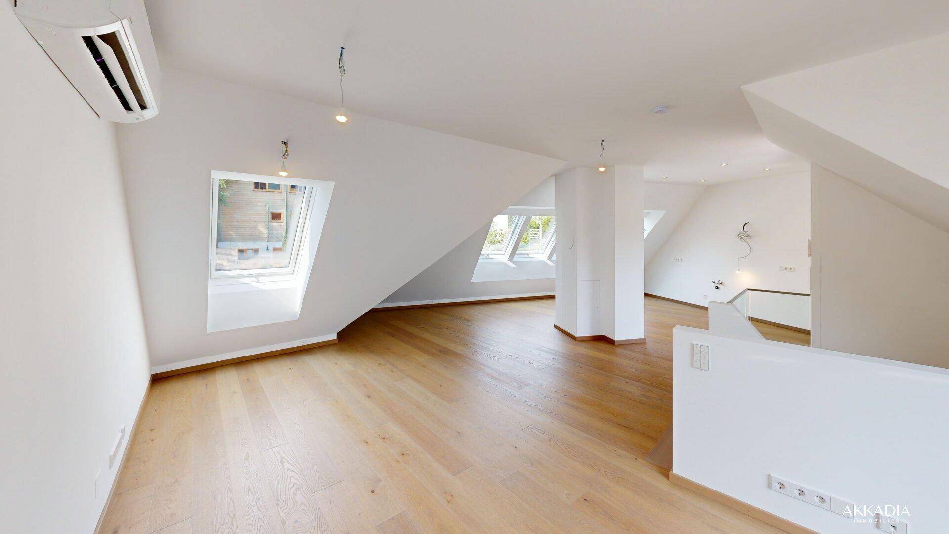 Geräumiger Dachgeschossraum mit Holzparkett, Dachschrägen und mehreren Dachfenstern für viel Licht.