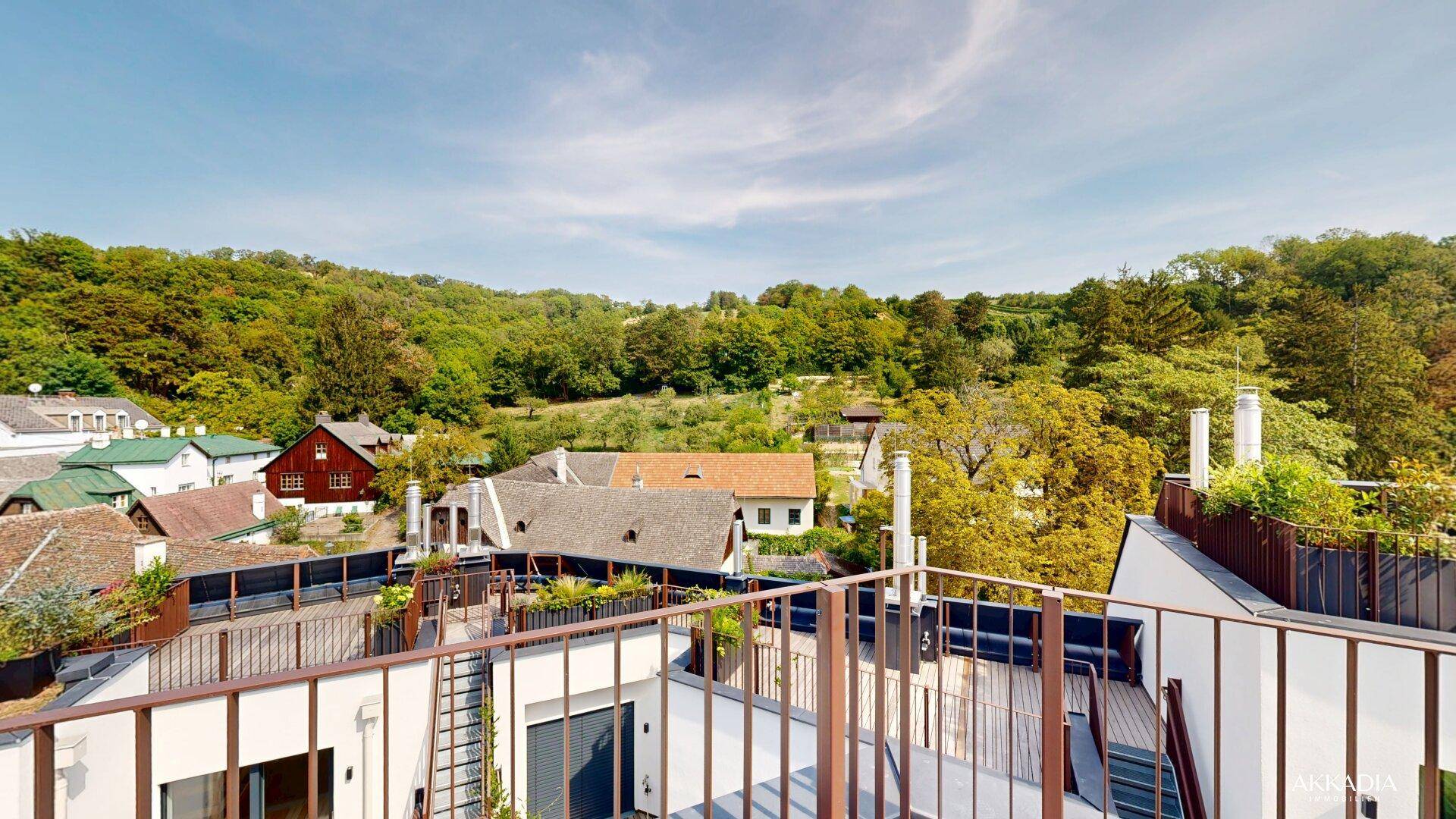 Dachterrasse mit weitem Blick über die Dächer und die umliegende grüne Landschaft.