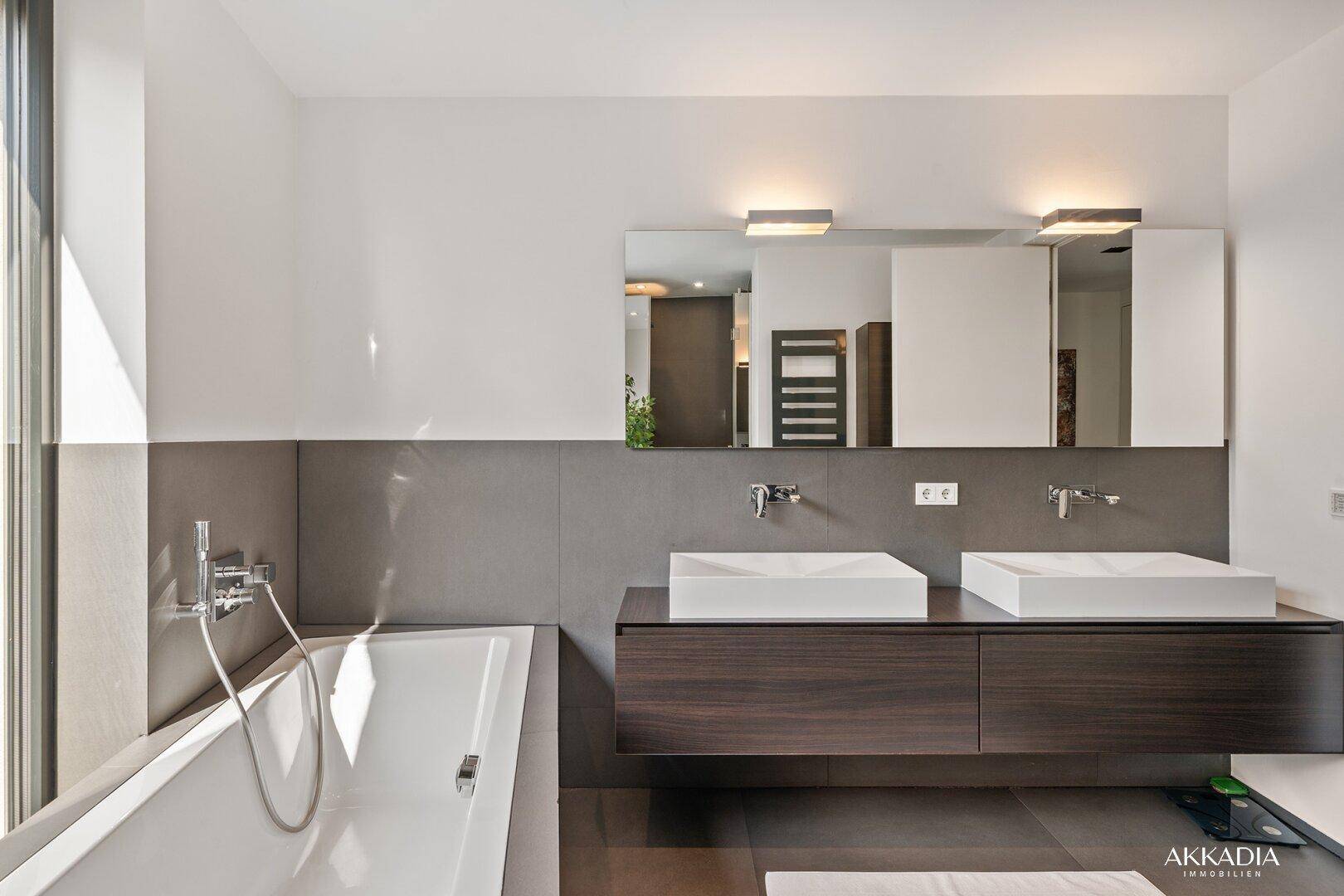 Modernes Badezimmer mit Doppelwaschbecken, Badewanne und großem Spiegel über dem Waschtisch.