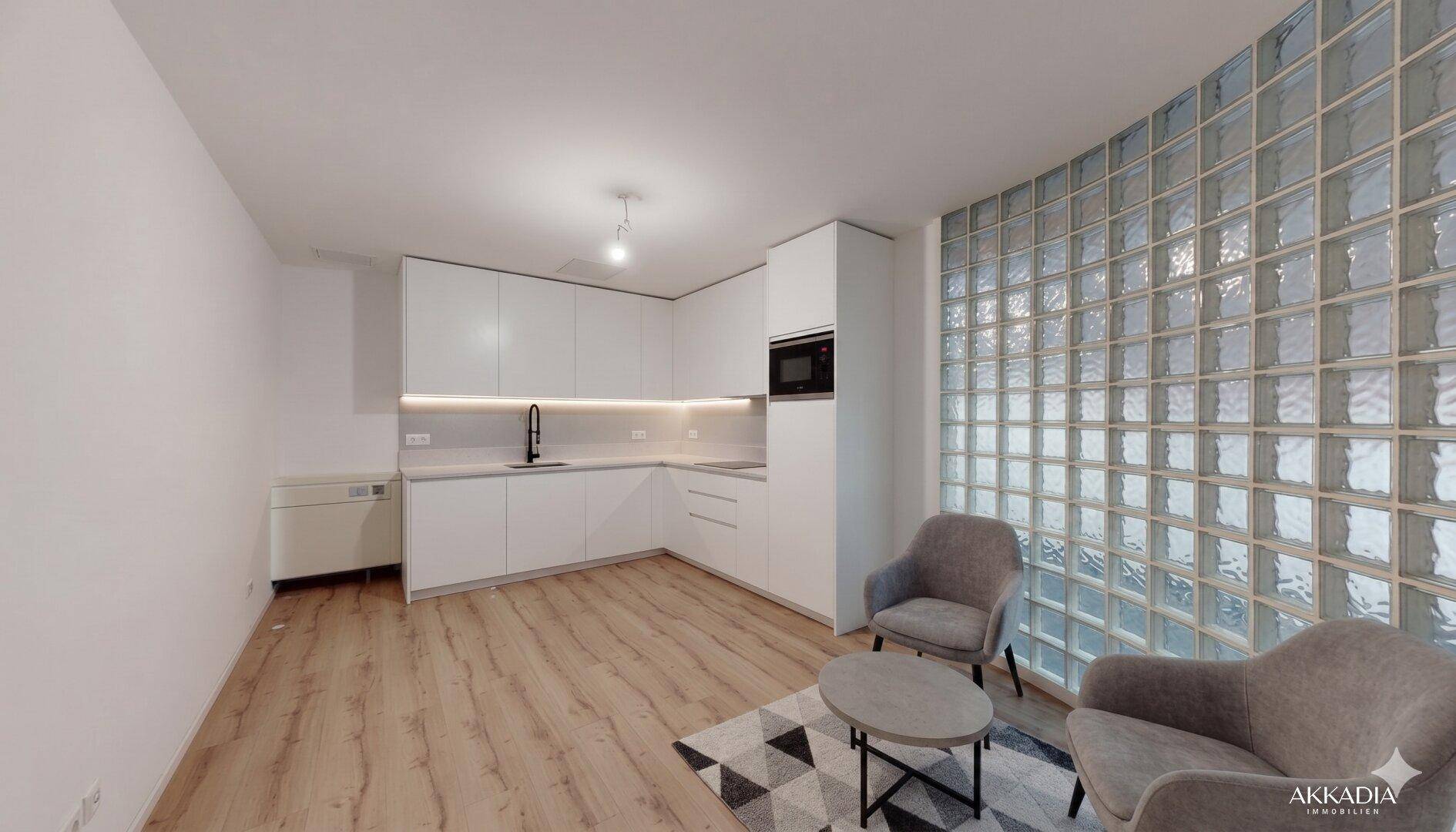 Moderne Küchenzeile mit weißen Schränken, integrierten Geräten und einer Glasbausteinwand.