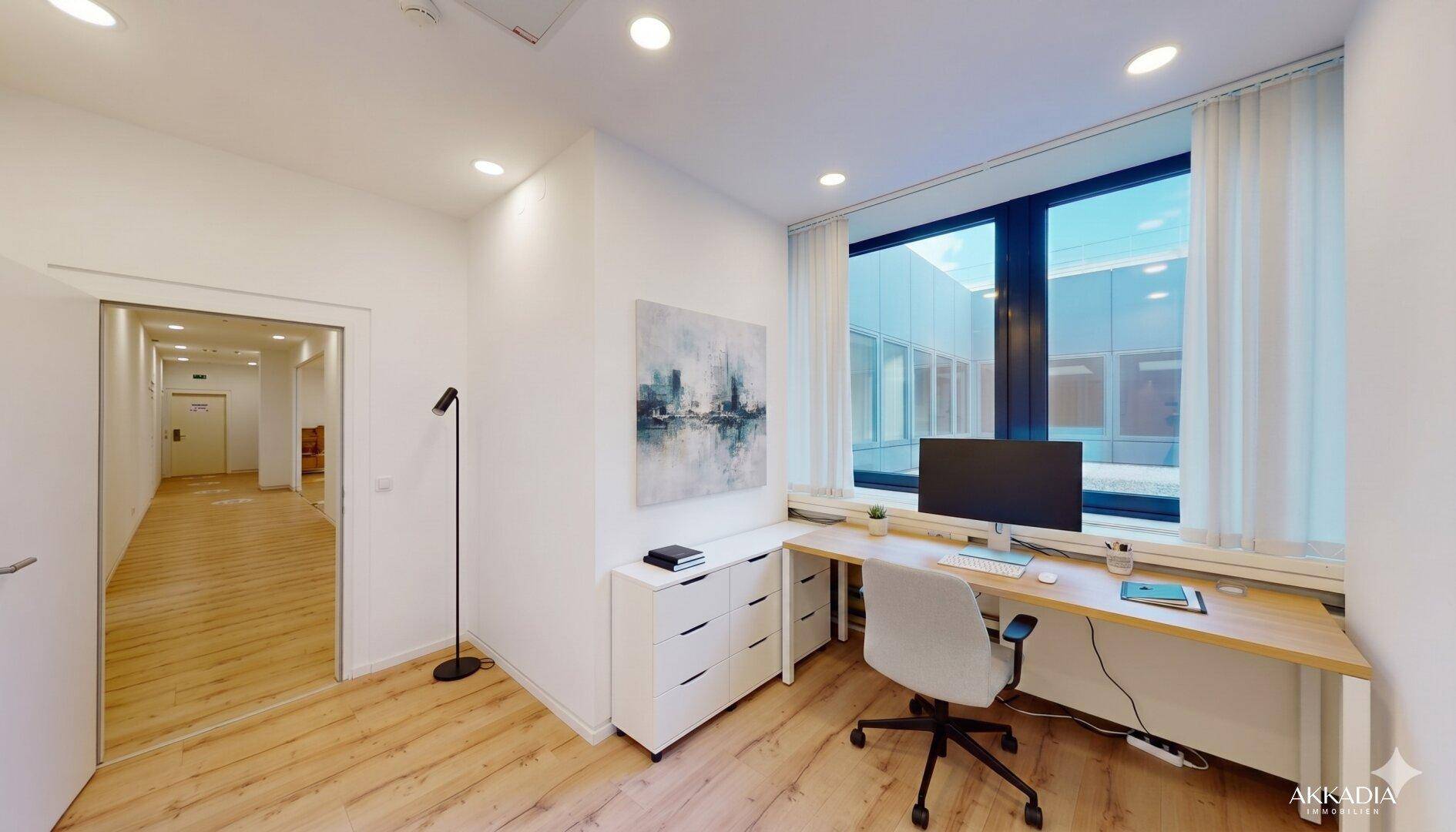 Einzelbüro mit Schreibtisch, Bürostuhl und einem großen Fenster mit Blick nach draußen.