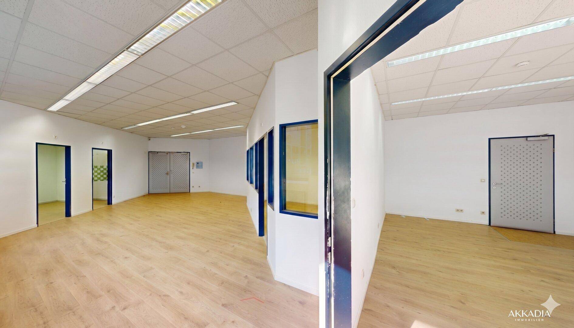 Geräumiger Bürobereich mit Holzboden und mehreren Türen, bietet flexible Raumgestaltung.