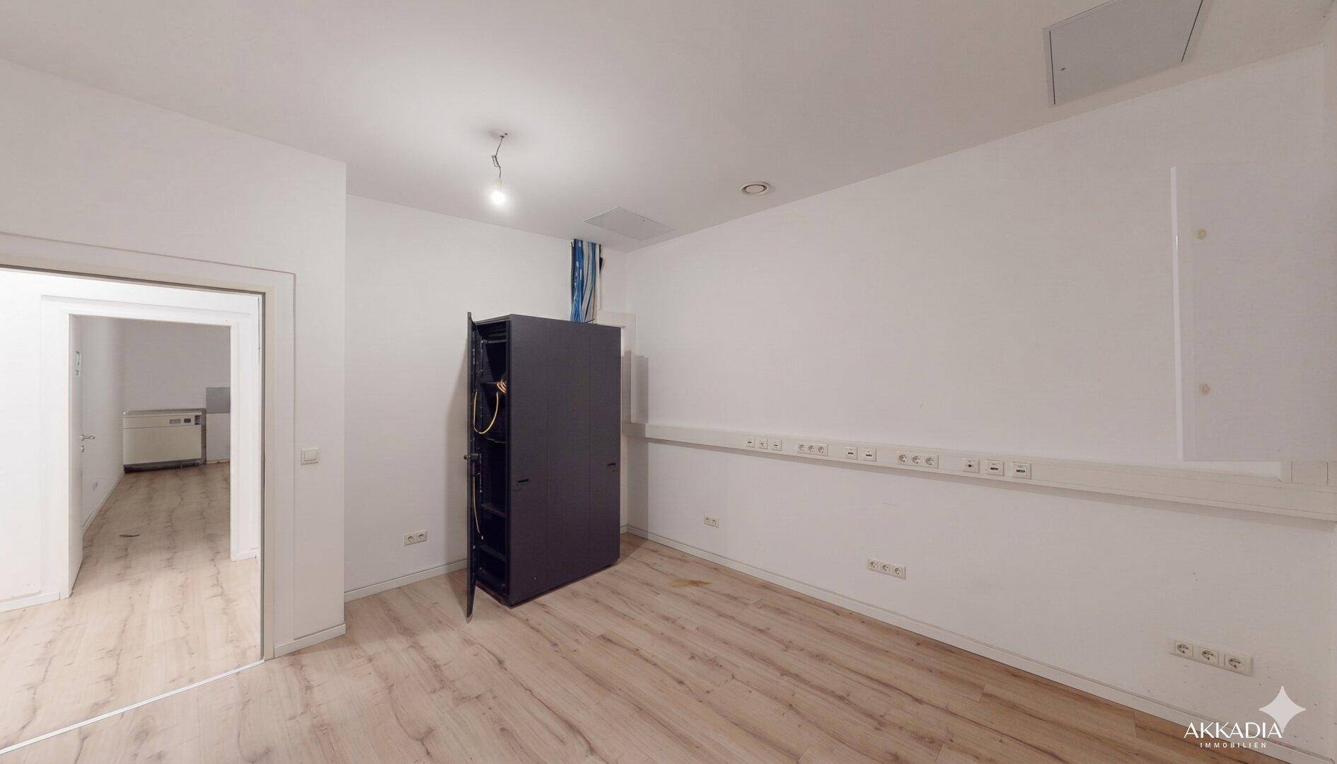 Technischer Raum mit Serverrack und zahlreichen Steckdosenleisten entlang der Wände.