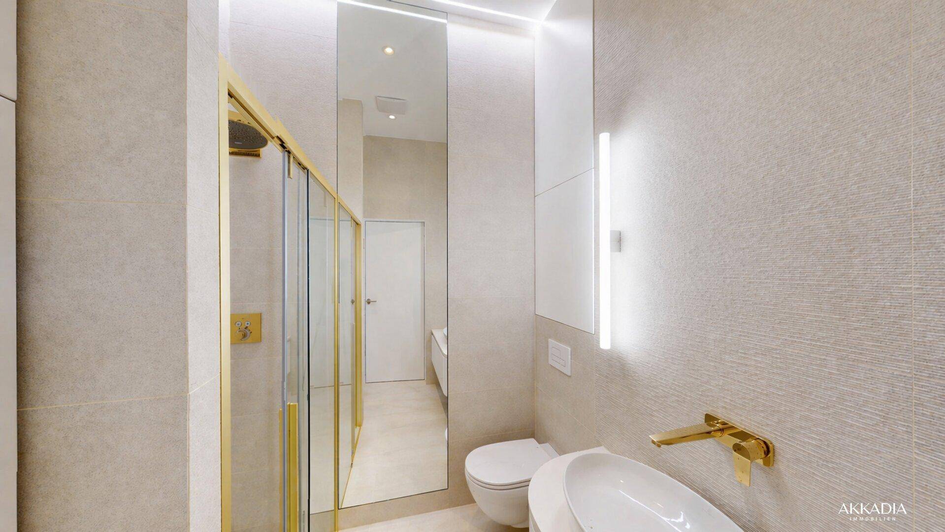 Elegantes Badezimmer mit begehbarer Dusche, modernen Fliesen und goldenen Armaturen in hellem Design.