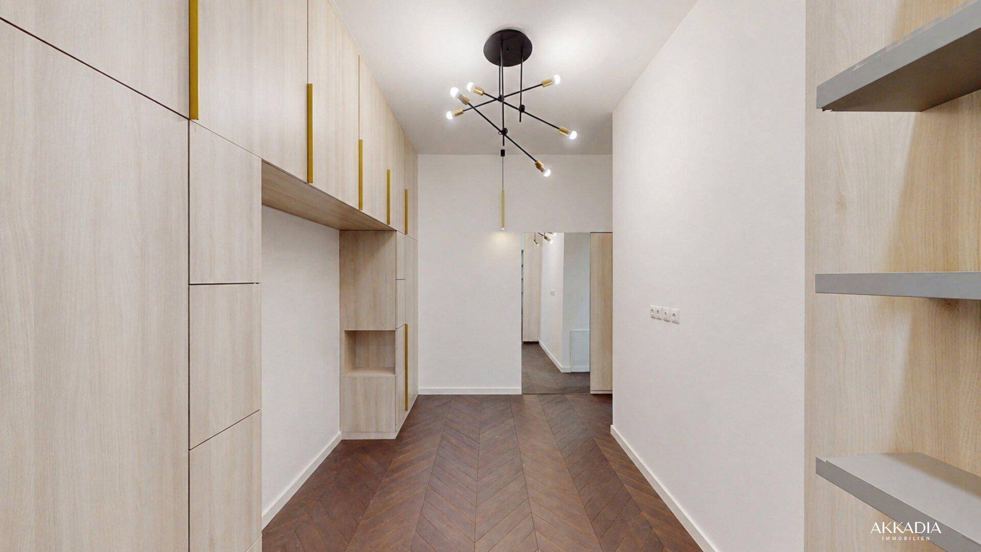Heller Flur mit integrierten Schränken, modernem Lichtdesign und Fischgrätparkettboden.