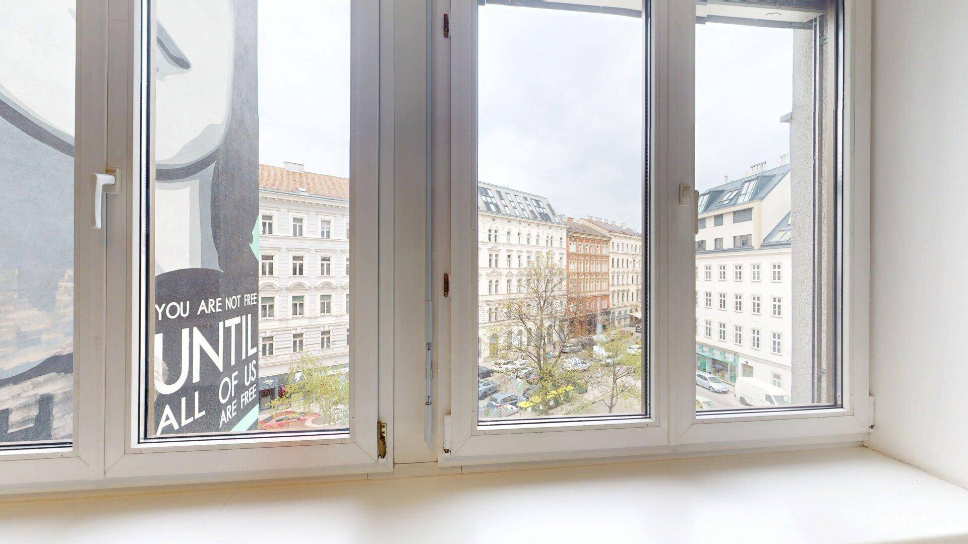 Fenster mit Blick auf die umliegenden Gebäude und die Stadtlandschaft, mit einem Schriftzug auf der Scheibe.
