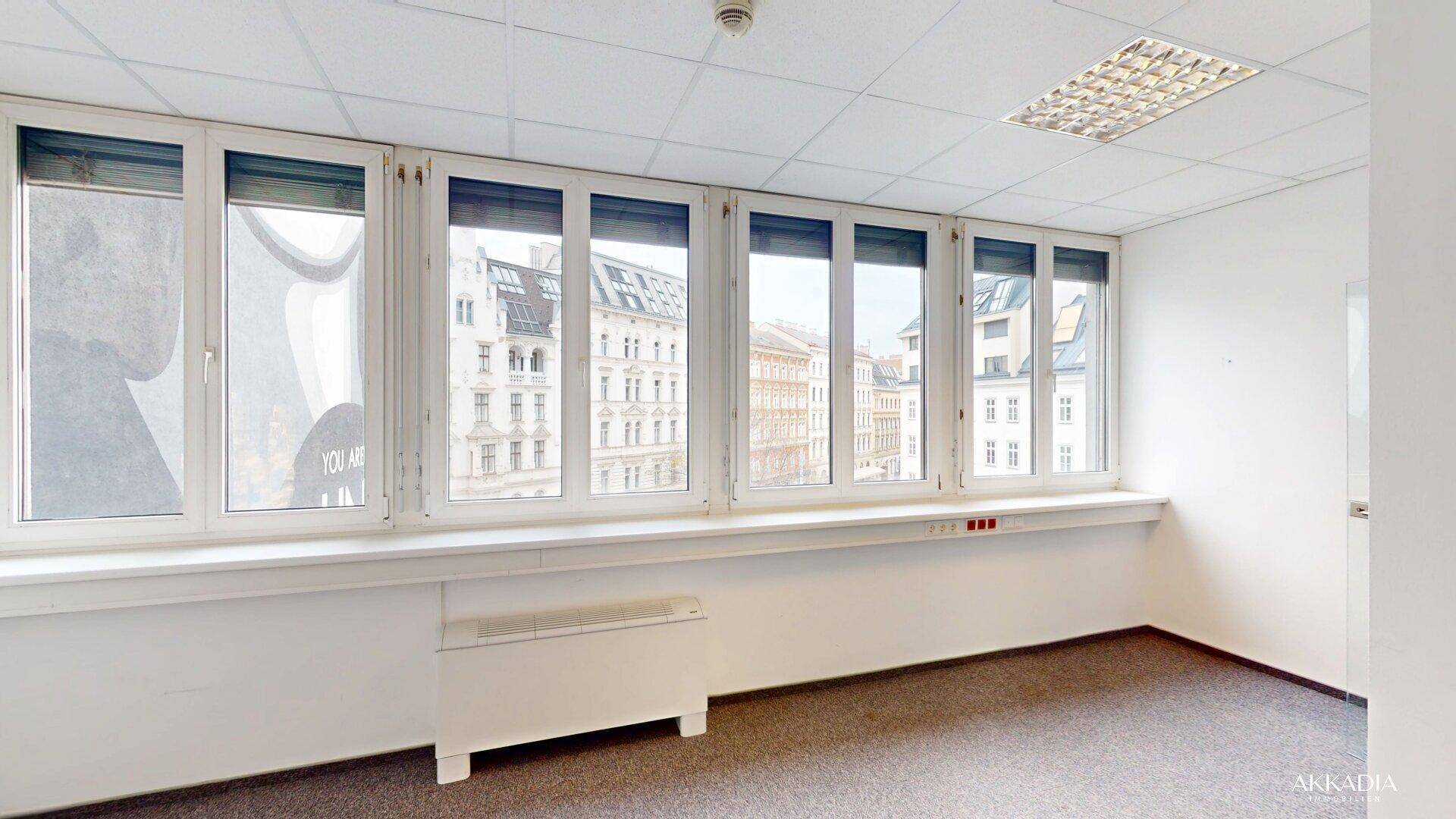 Langes Büro mit vielen Fenstern, die viel Tageslicht hereinlassen, und einem Heizkörper unter der Fensterbank.