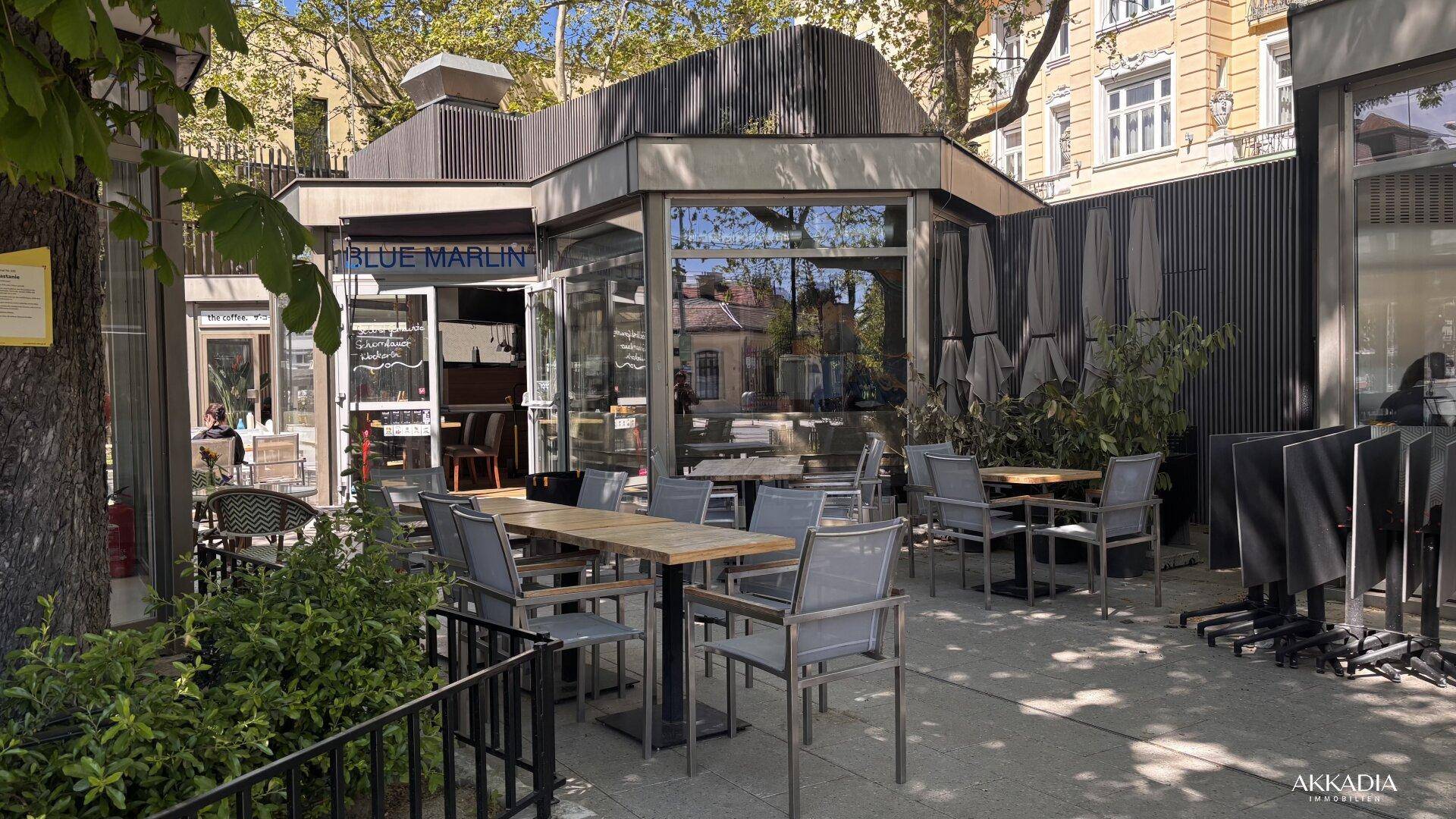 Leere Außenterrasse eines Restaurants mit Tischen und Sonnenschirmen, bereit für Gäste.