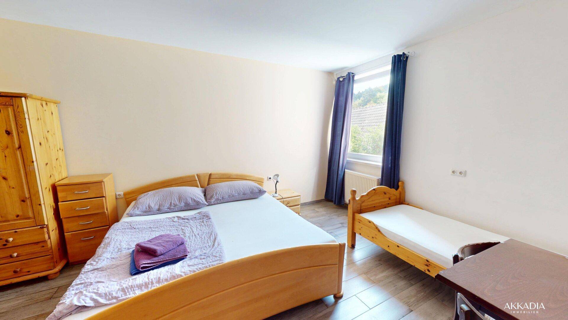 Geräumiges Schlafzimmer mit Doppelbett, zusätzlichem Einzelbett und Holzfußboden.