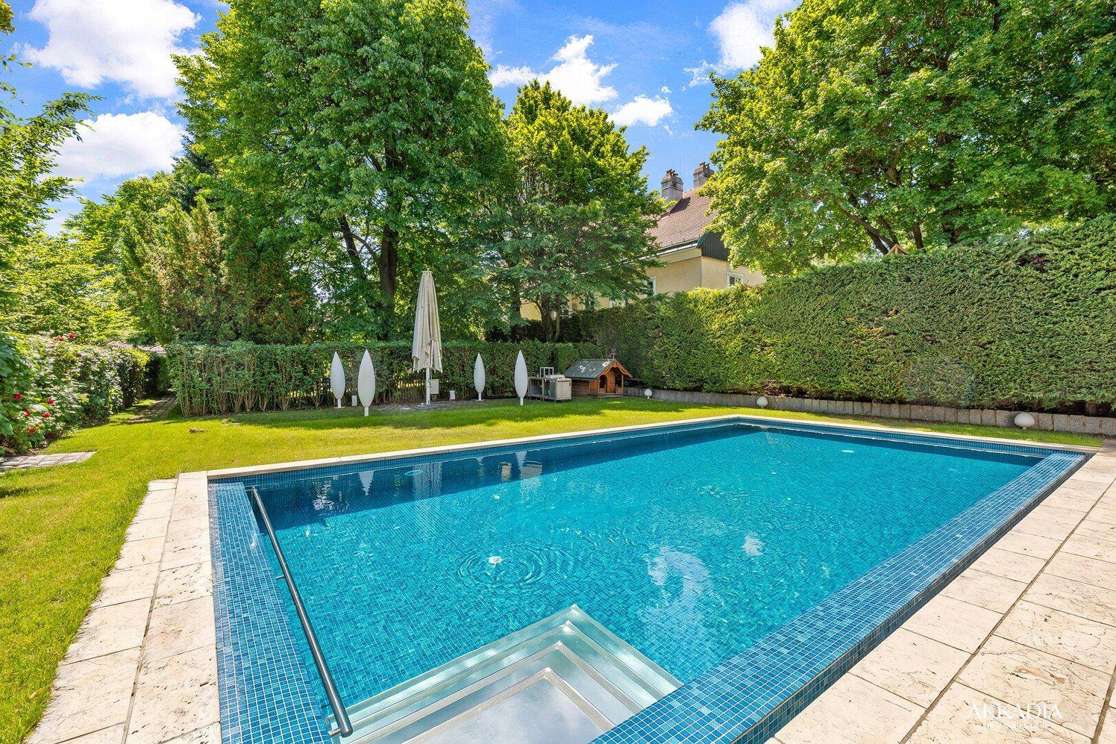 Großer Garten mit gepflegtem Rasen, hohen Hecken und einem einladenden Swimmingpool.