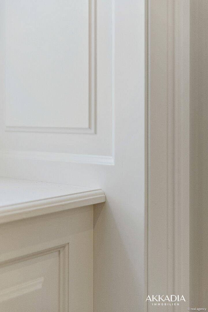Elegante weiße Wandverkleidung mit Zierleisten, die einen klassischen und gepflegten Eindruck vermittelt.