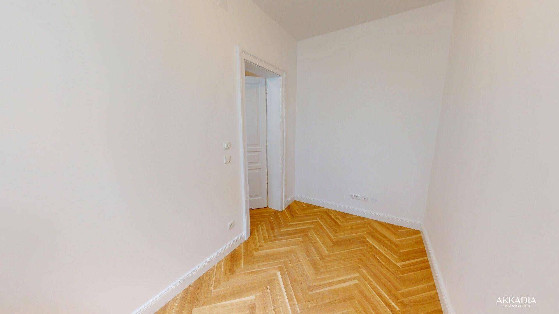 Ruhiges Zimmer mit klassischem Fischgrätparkett und weiß gestrichenen Wänden, ideal als Schlaf- oder Arbeitszimmer.