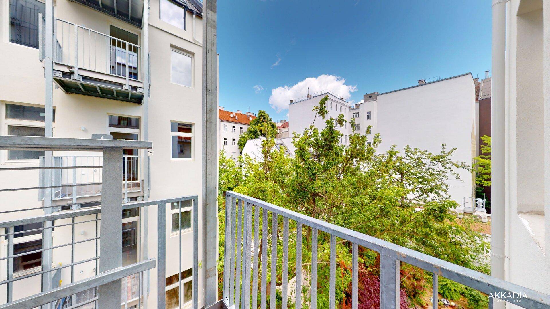Balkon mit Blick auf grüne Bäume und die umliegenden Gebäude der Stadt.