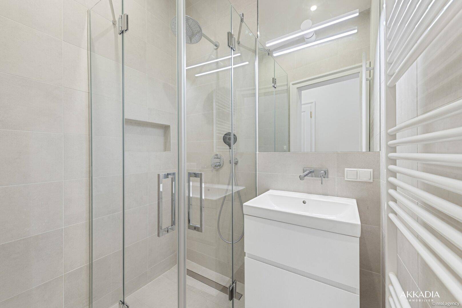 Helles Badezimmer mit moderner Glasdusche, Einzelwaschbecken und großem Spiegel.