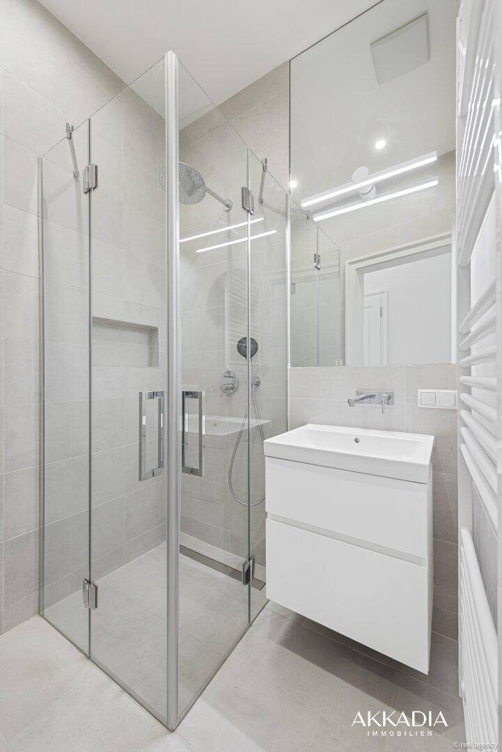 Modernes Badezimmer mit begehbarer Dusche, Einzelwaschbecken und beheiztem Handtuchhalter.