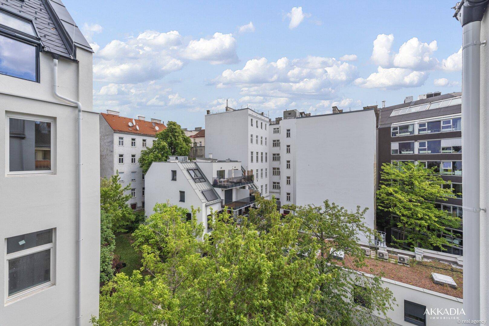 Blick über die Dächer der Stadt mit viel Grün und umliegenden Gebäuden.