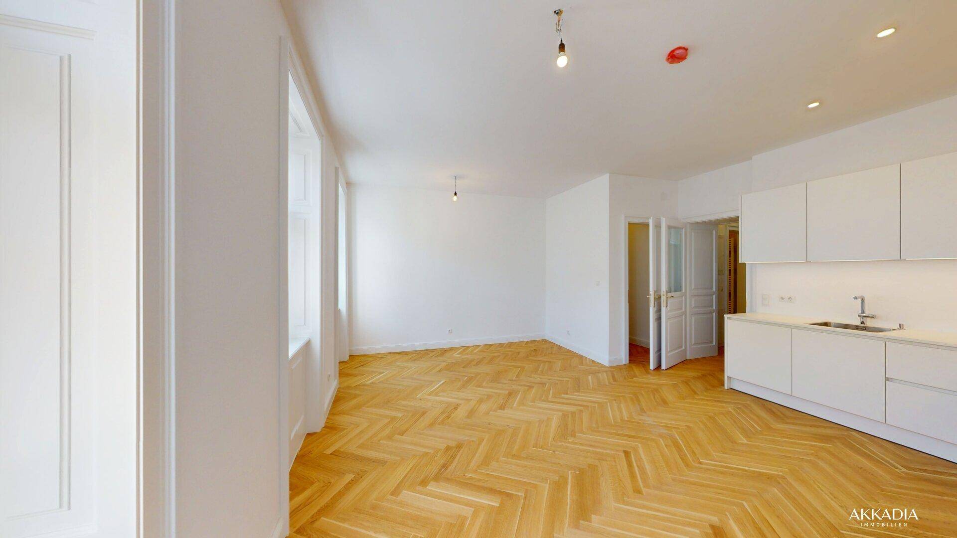 Geräumiger, heller Wohnbereich mit Fischgrätparkett und hohen Fenstern, bereit zur individuellen Gestaltung.
